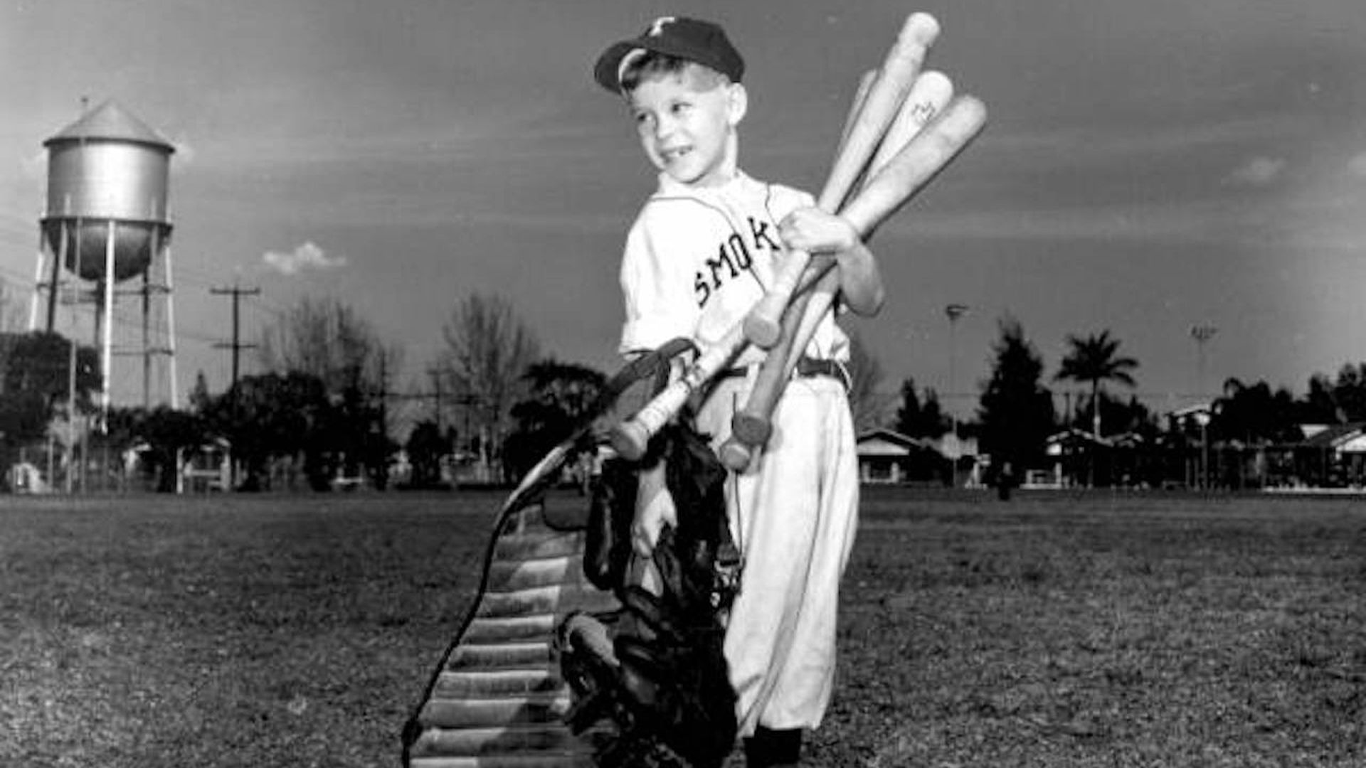 black and white photo of a child holding bats in a  Smokers uniform