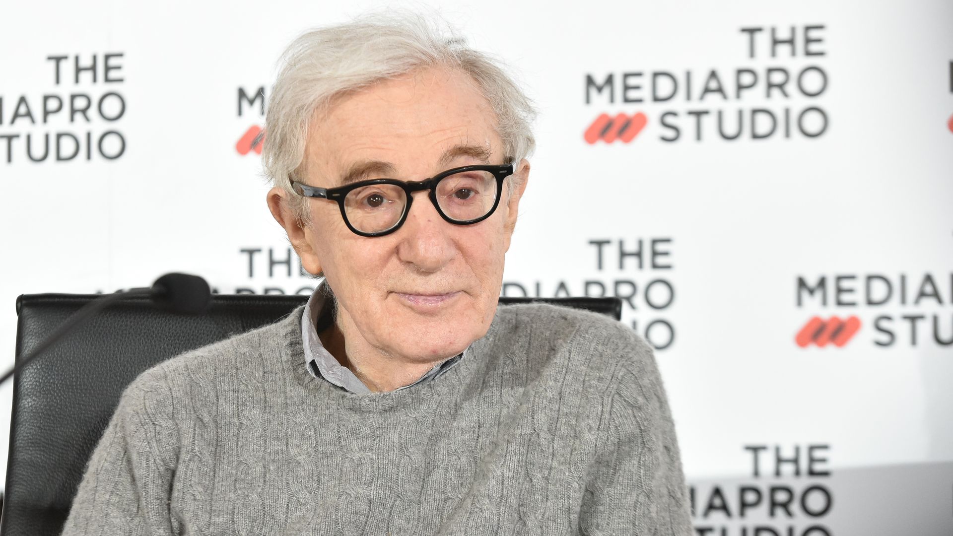 In this image, Woody Allen sits in a sweater