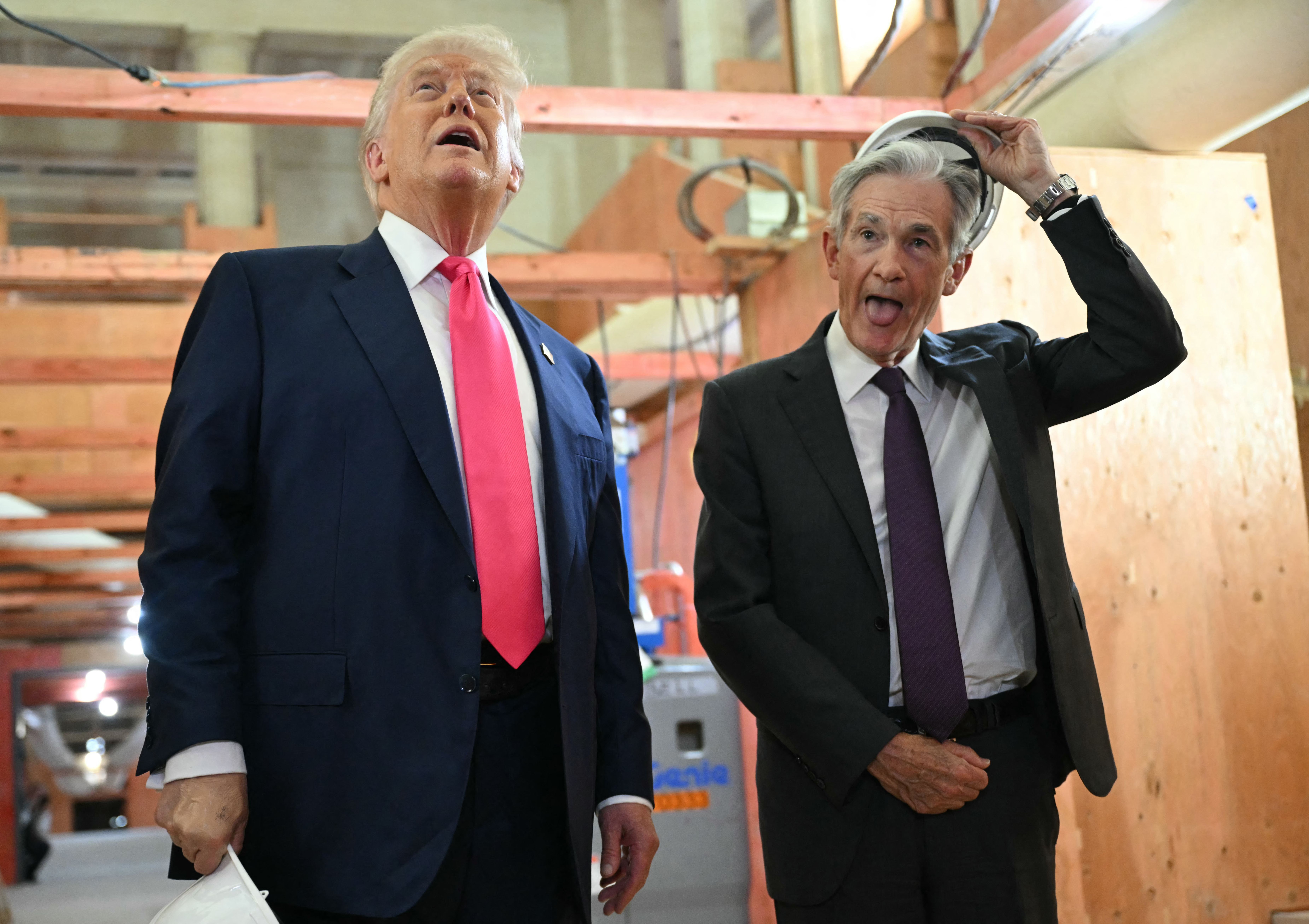 Fed chair Jay Powell sticks out his tongue while taking off his hard hat.
