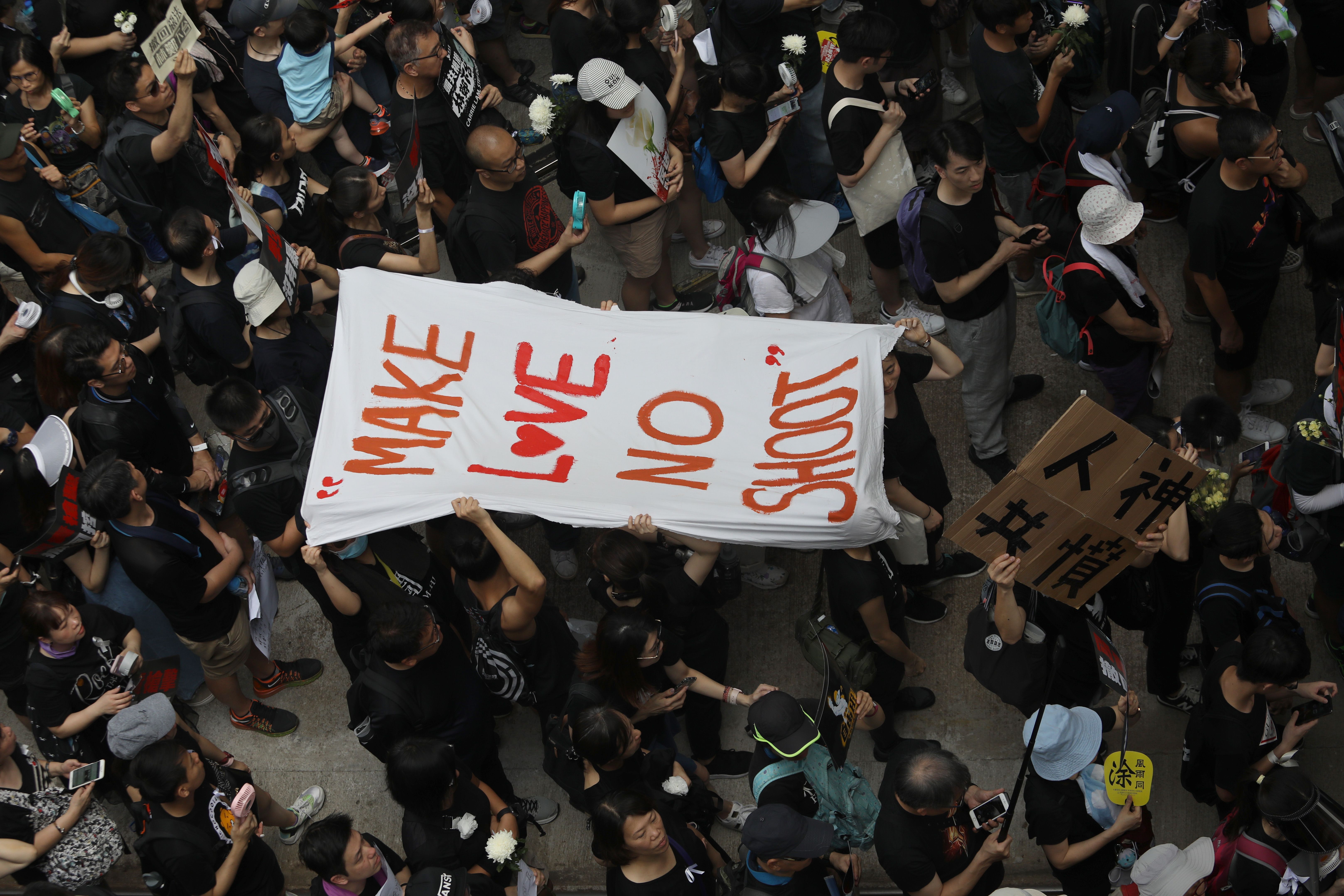 People carry a banner reading "Make love no shoot".