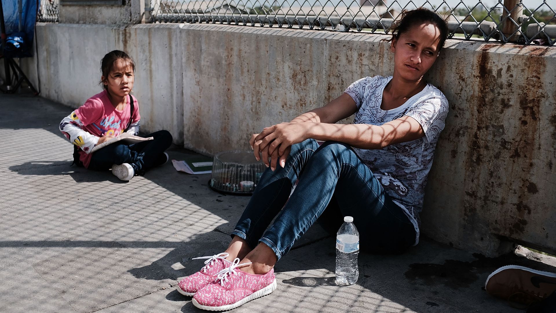 A woman sits with a child on a bridge.