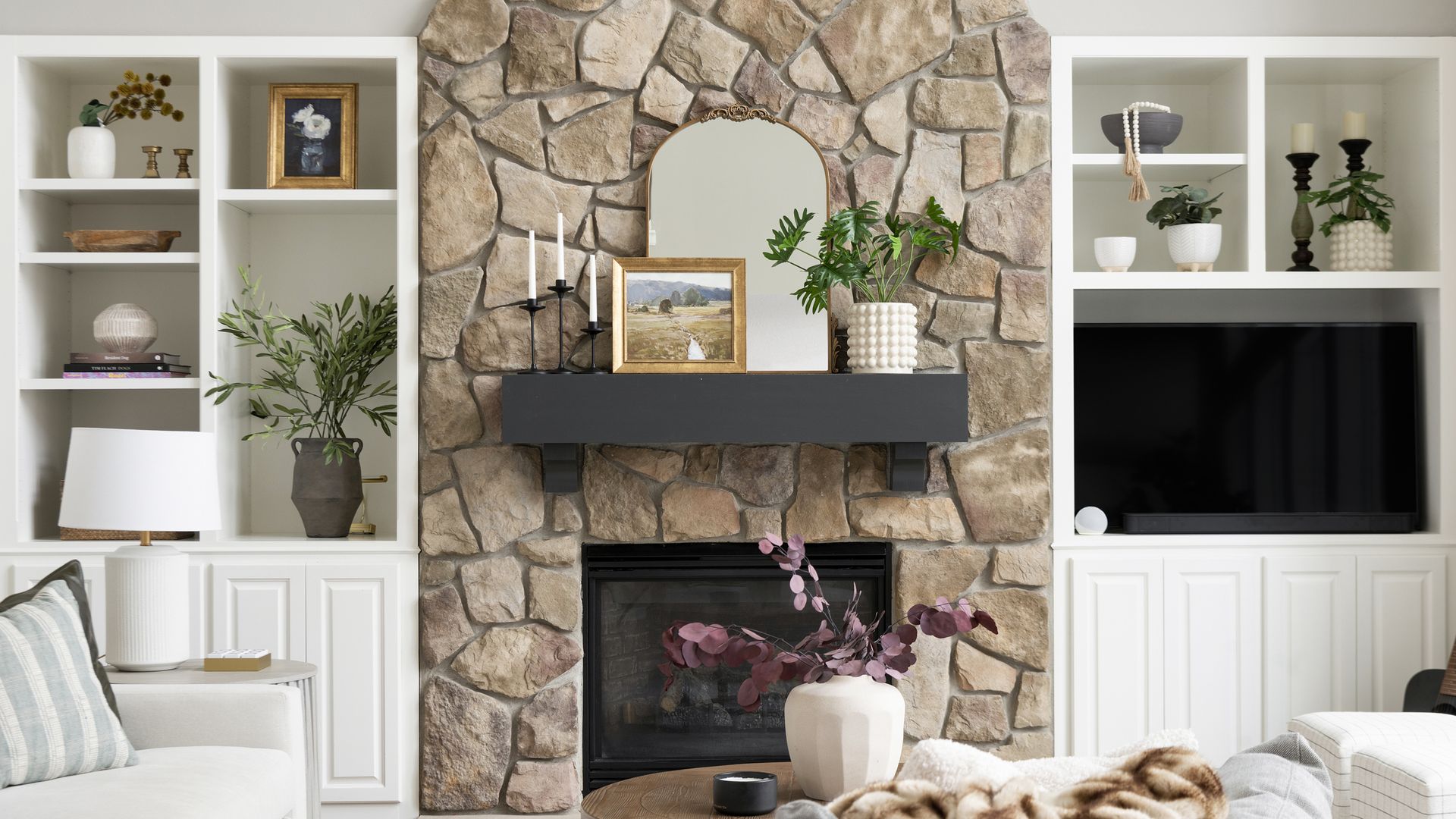 professionally designed living room with stone fireplace and open shelving