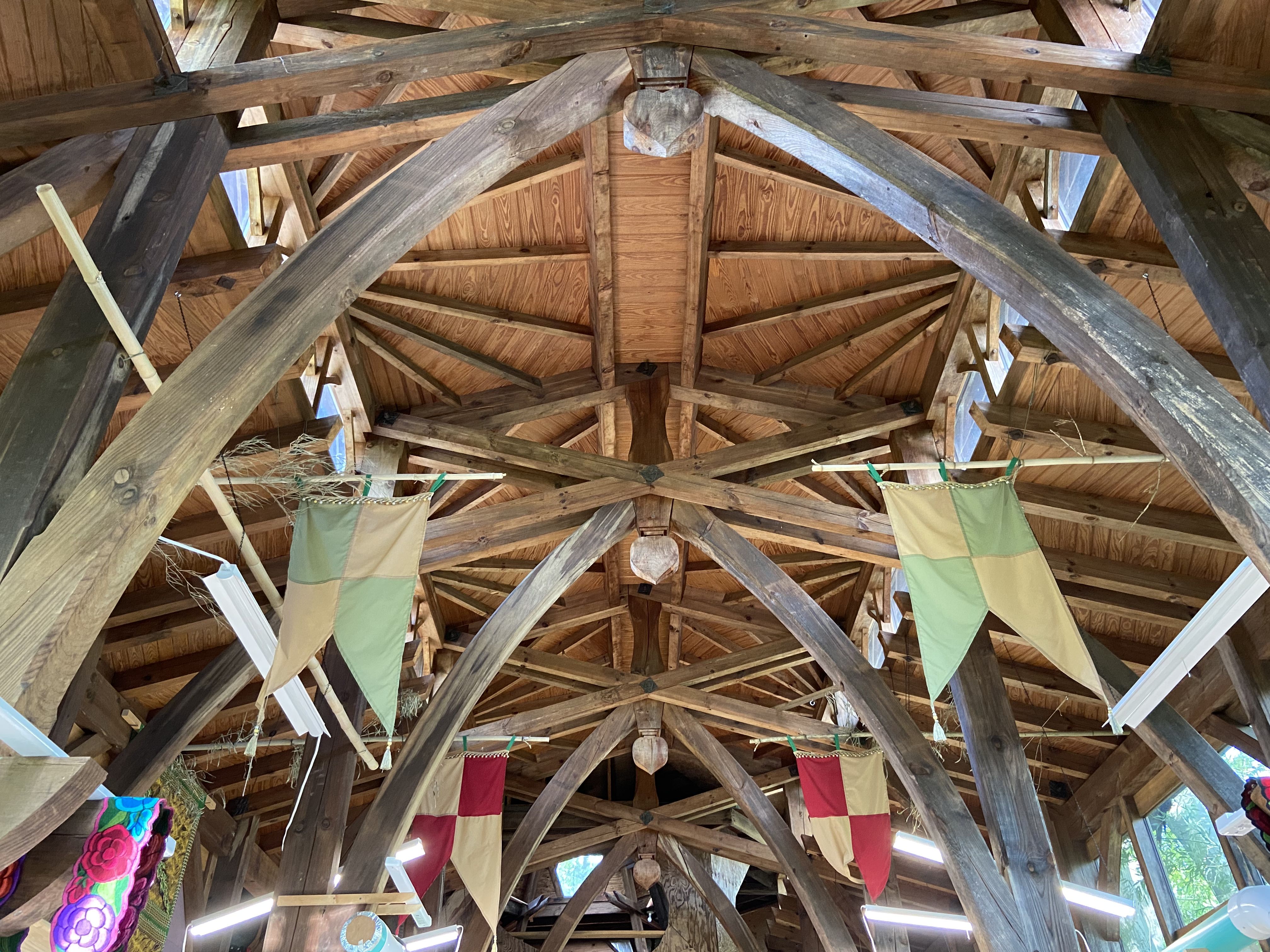 A photo looking up at a large medieval-like ceiling with flags