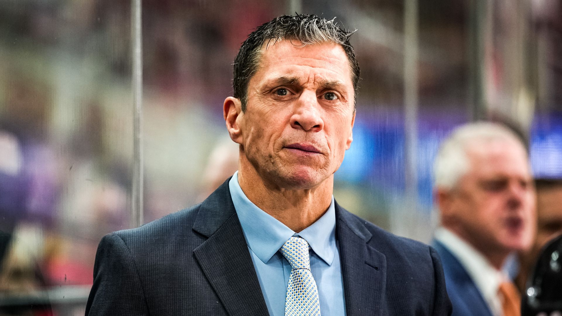 Head coach Rod Brind'Amour of the Carolina Hurricanes looks on during a game, smirking slightly. 