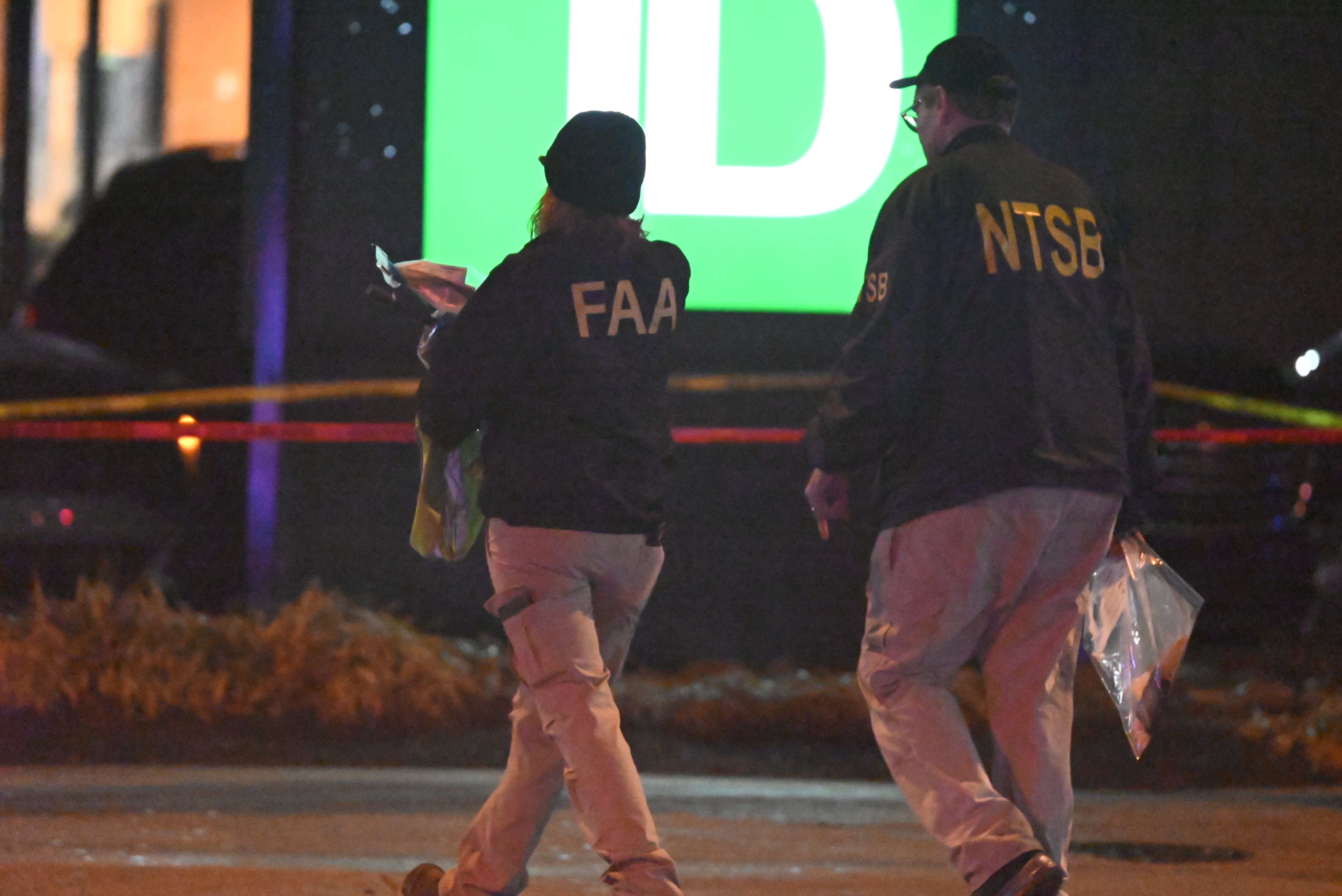 FAA and NTSB investigators carry a "material" evidence bag from the plane crash site in Northeast Phialdelphia.