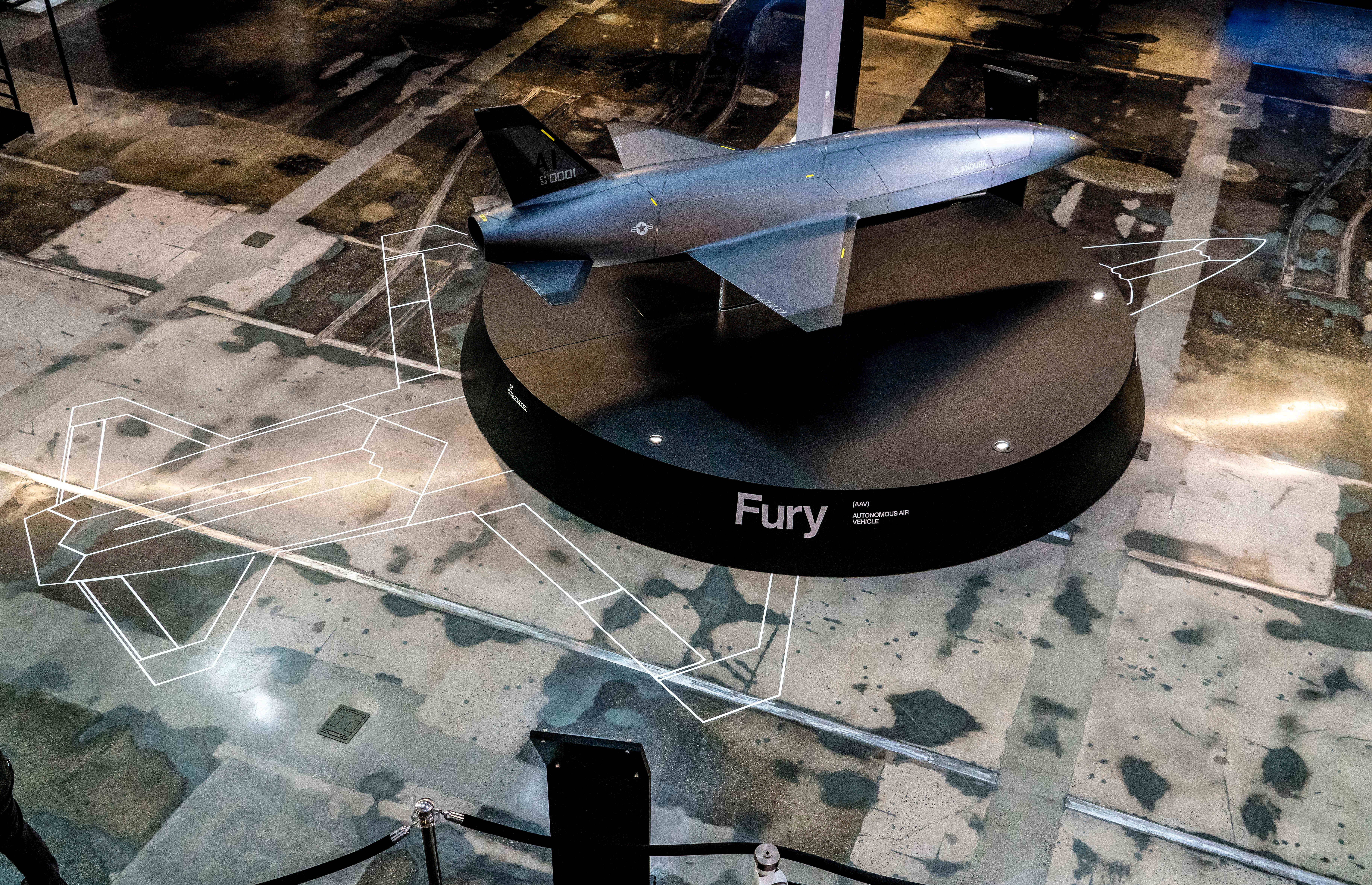 A scale model of an autonomous air vehicle that looks like a plane, located on top of a display platform.