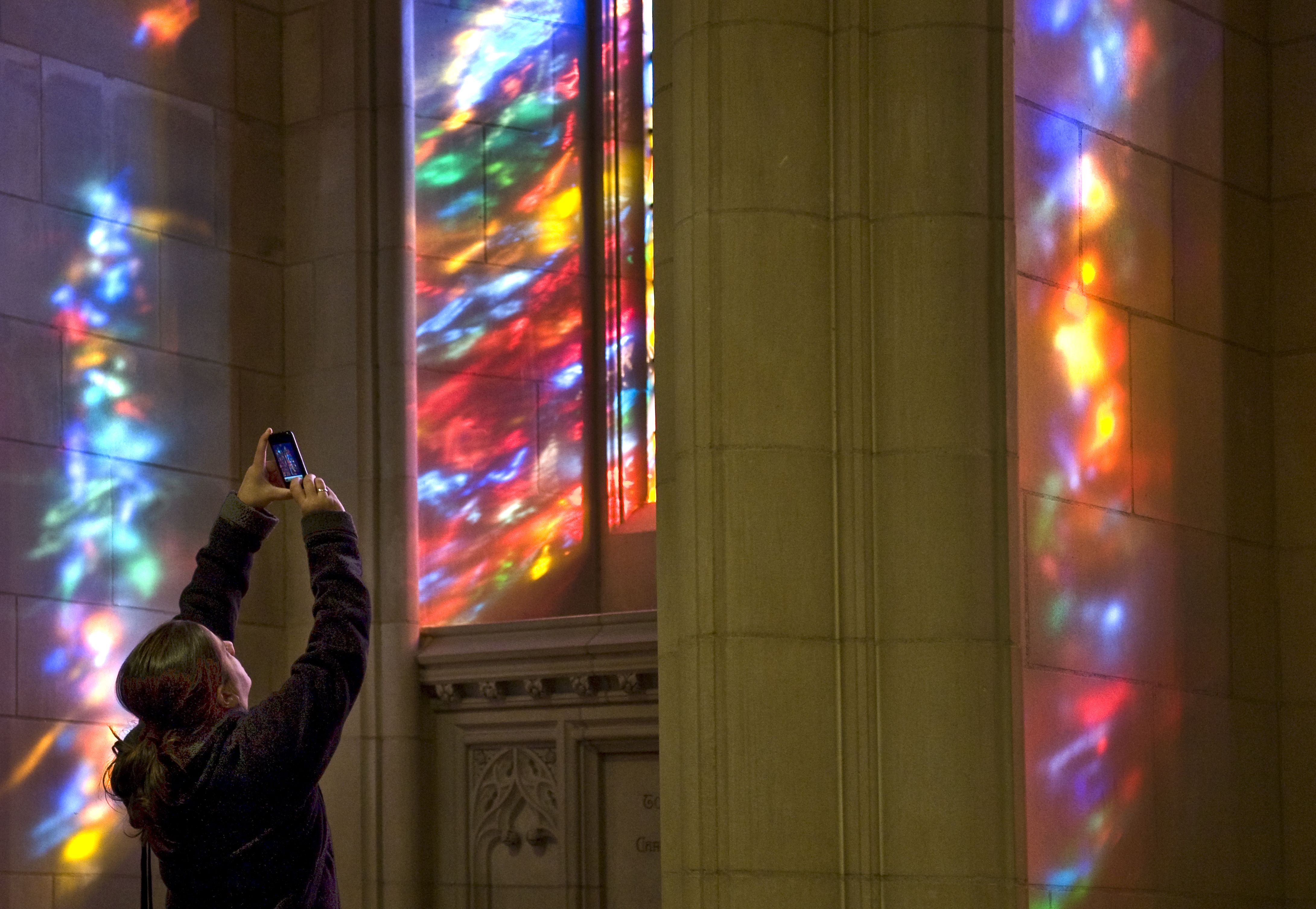 A person takes a picture of the stained glass