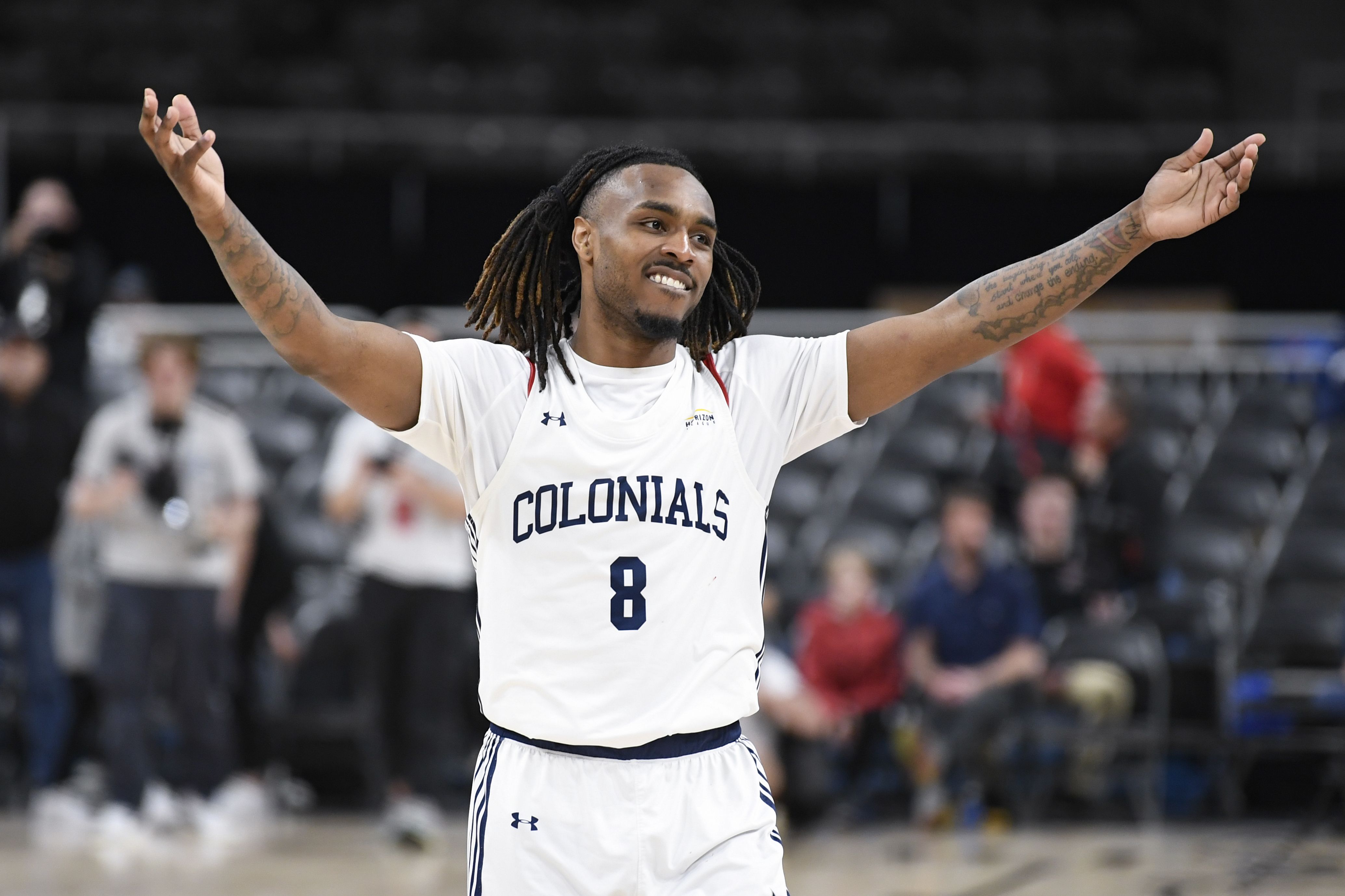 Photo of a man raising his hans in celebration on a basketball court. 