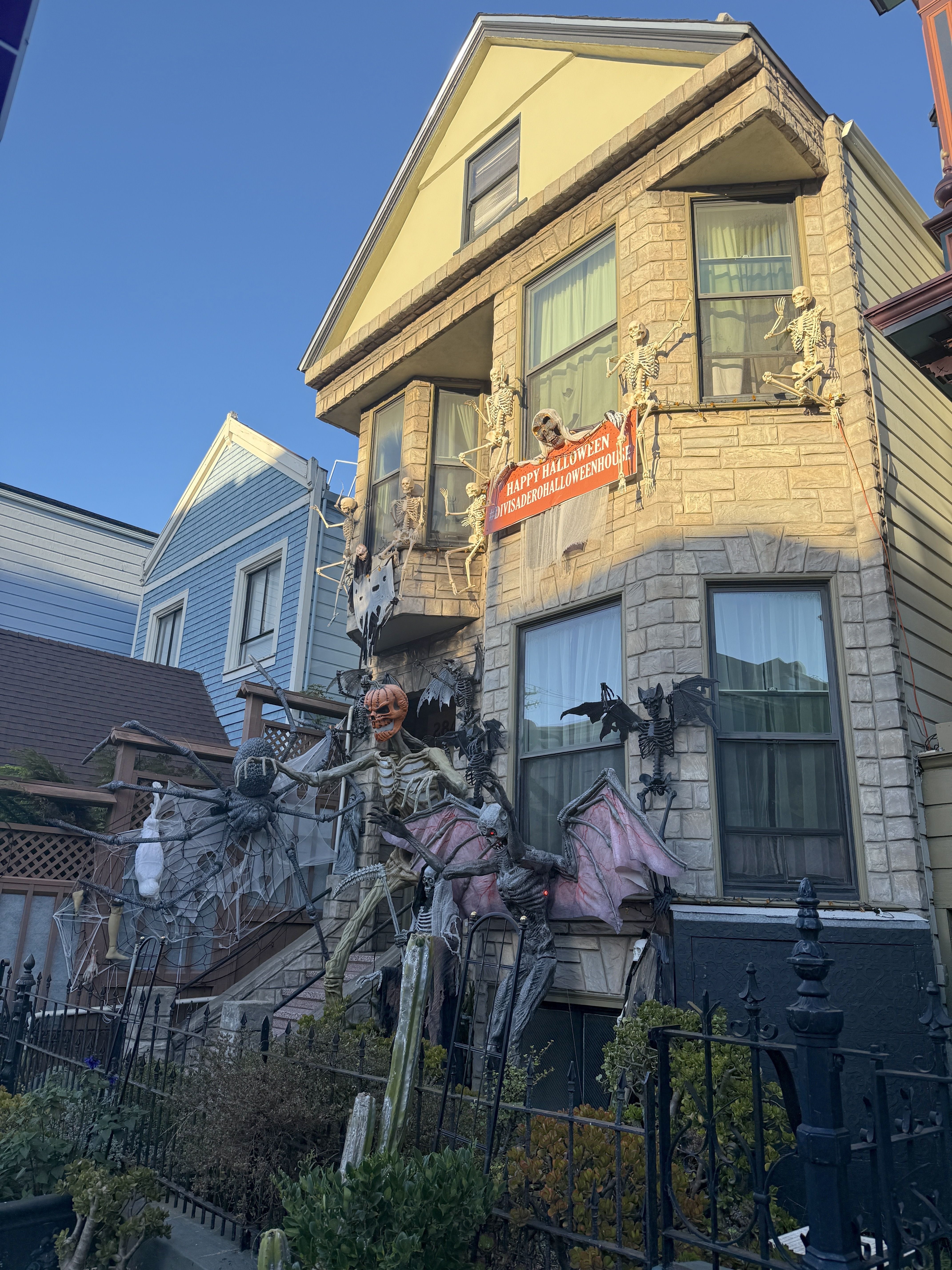 Photo of a two-story house decked out with Halloween decorations, including skeletons, bats and pumpkins