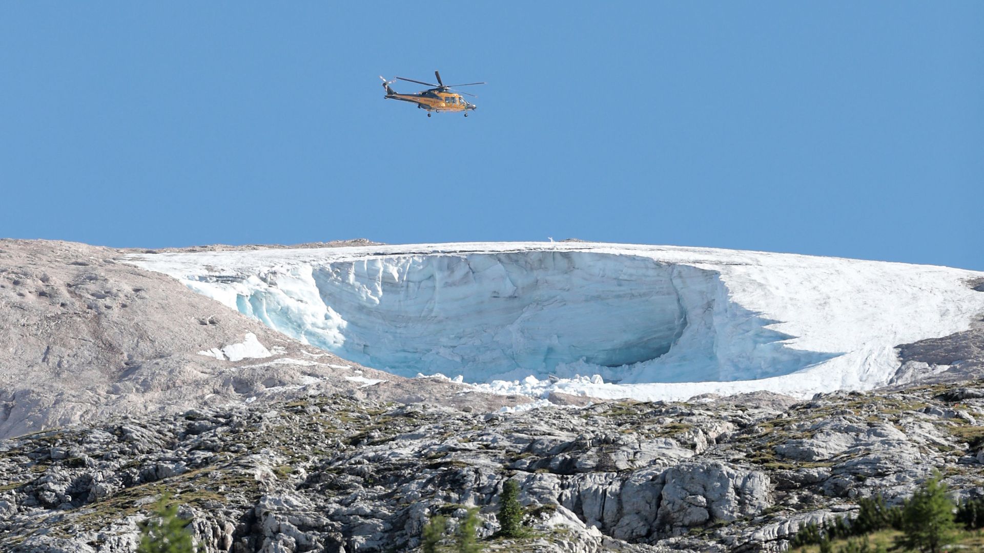 Rescue helicopter flies above the missing chunk of the Marmolada Glacier in Italy a day after its collapse. 