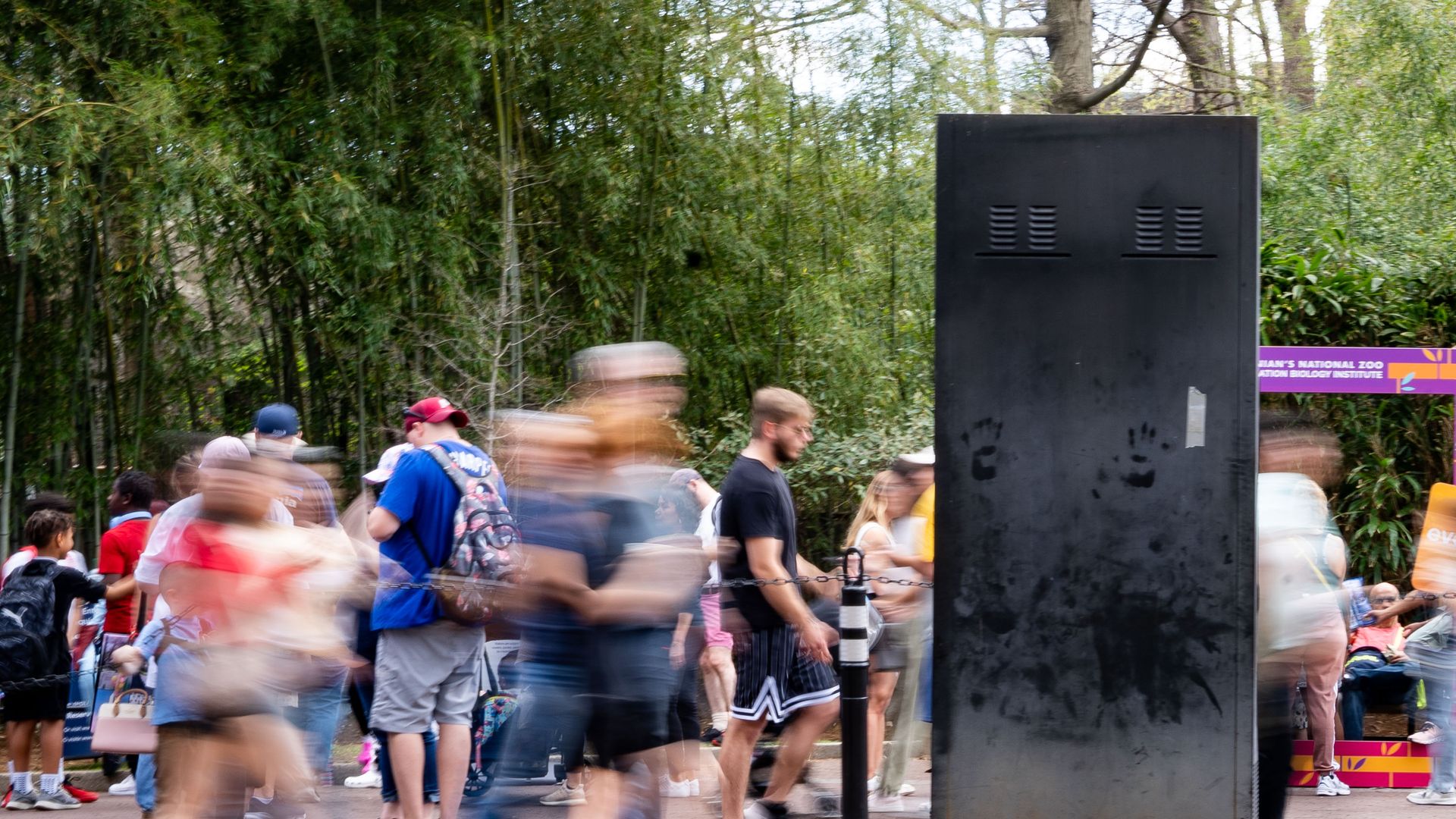 A photo of crowds walking past a sign at the National Zoo in Washington, D.C.