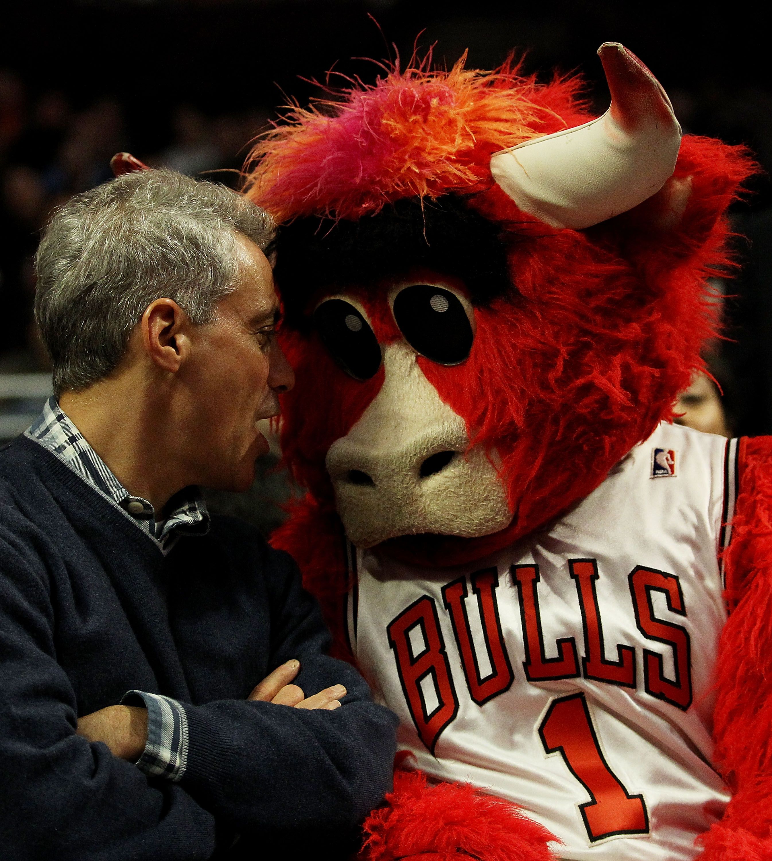 Photo of a man and a mascot watching a basketball game. 