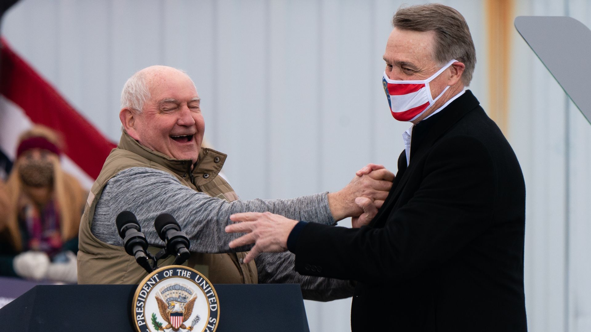 Sonny and David Perdue shaking hands and laughing