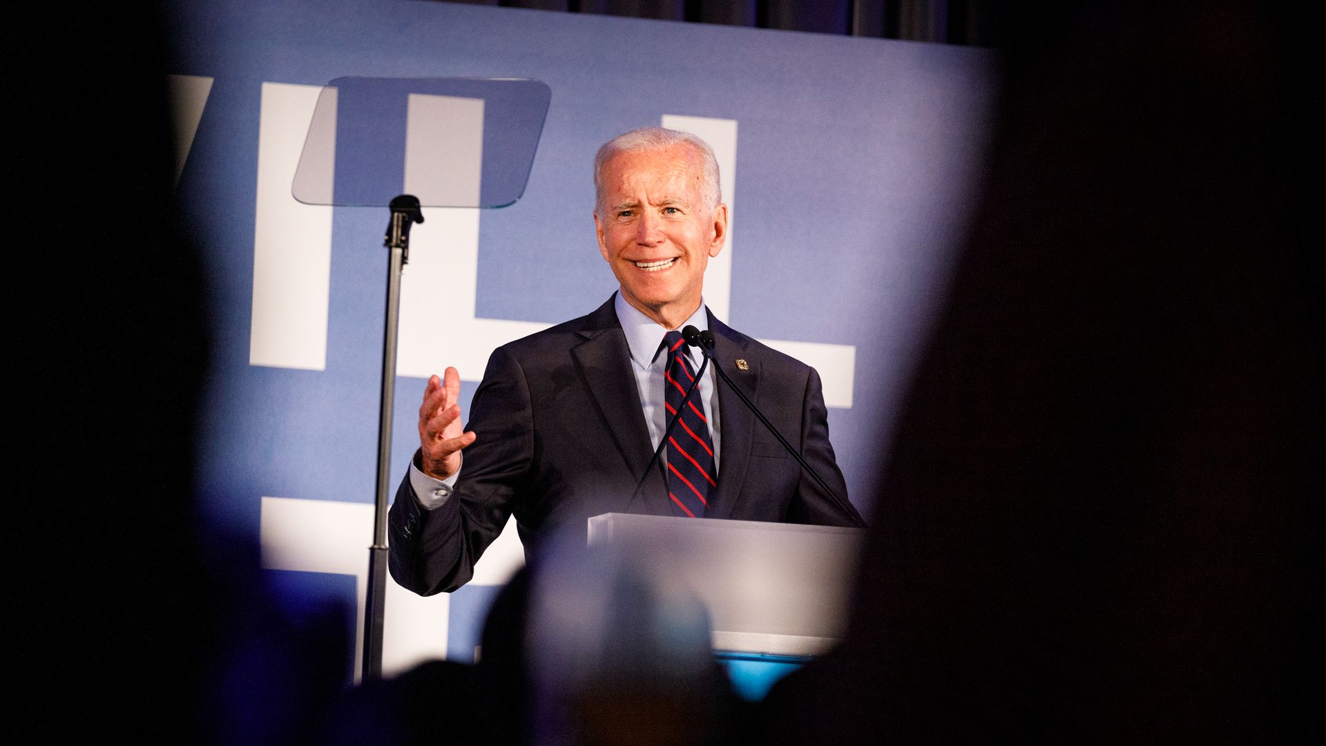 In this image, Biden stands framed by audience members at a podium