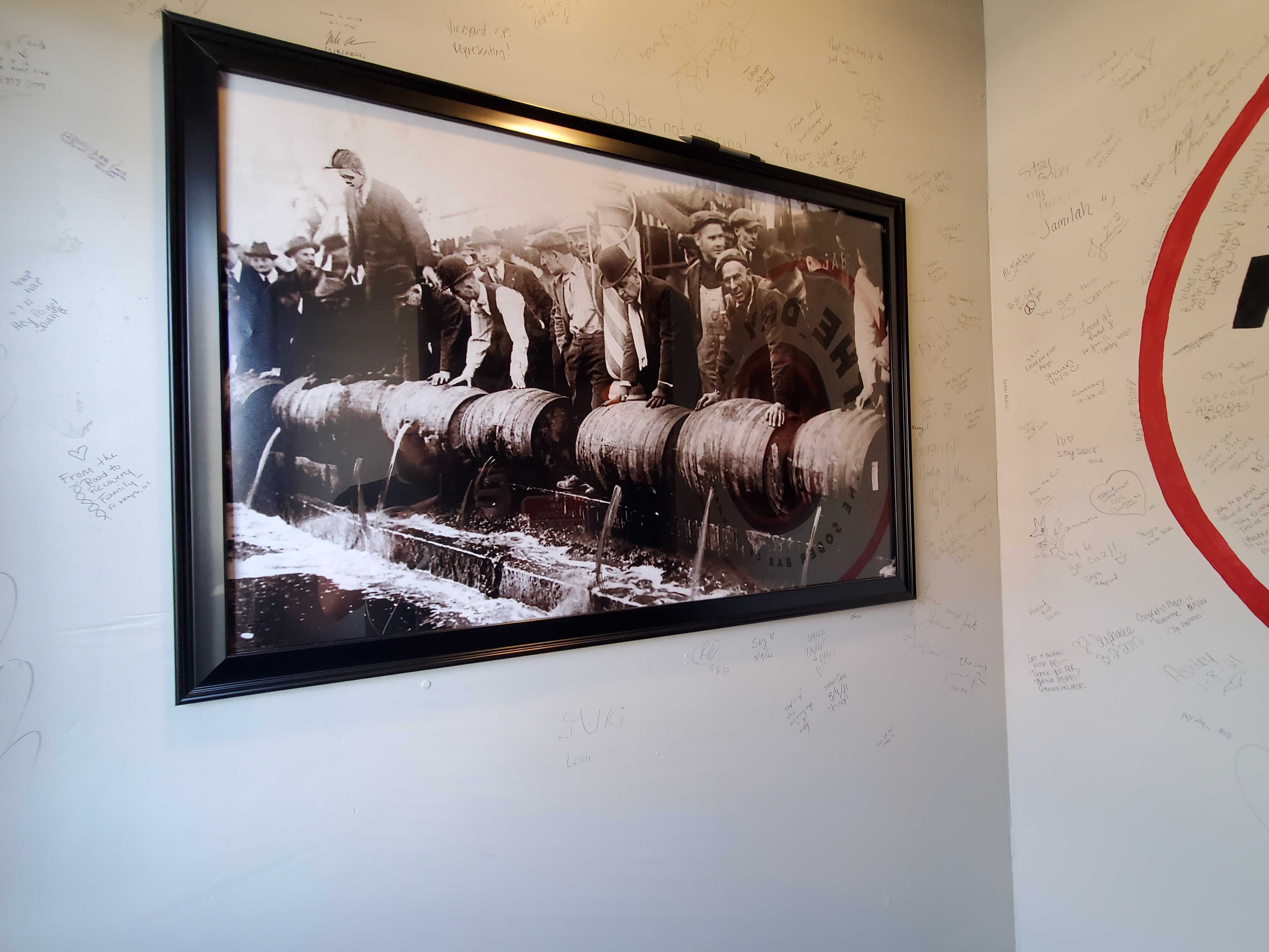 A framed photo on a bar's wall showing beer being poured out during Prohibition. 