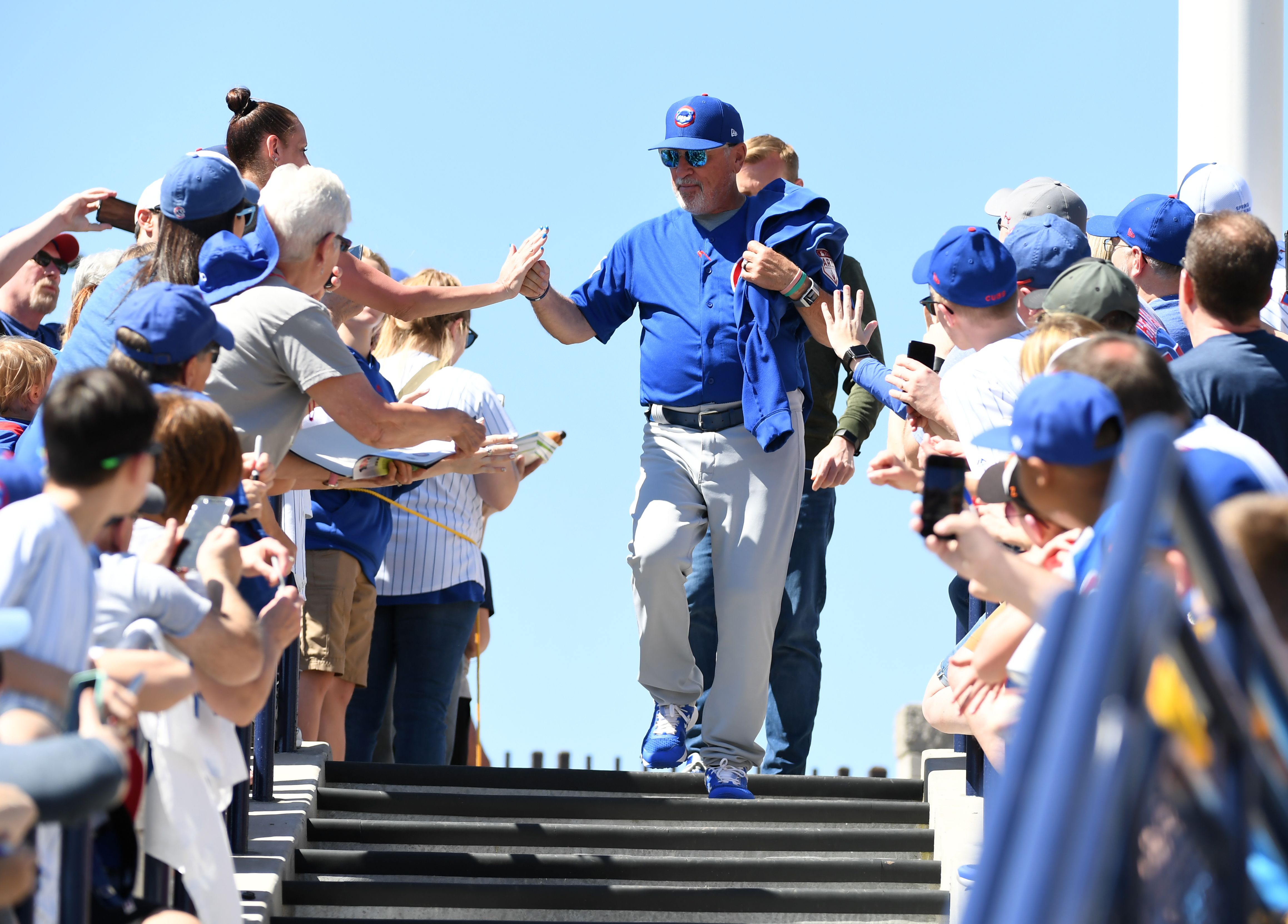 Photo of a baseball manager high-fiving fans. 