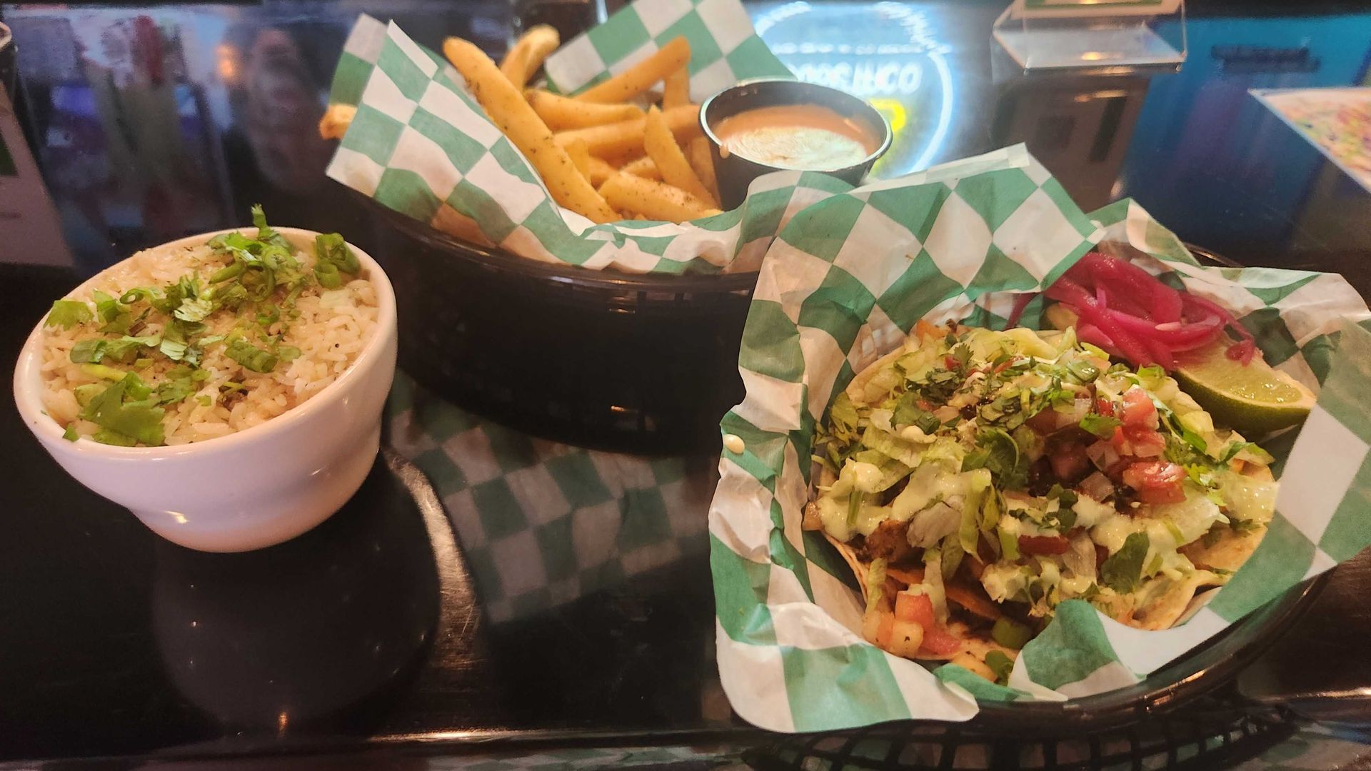 A taco, queso fries and side of rice on a diner countertop. 