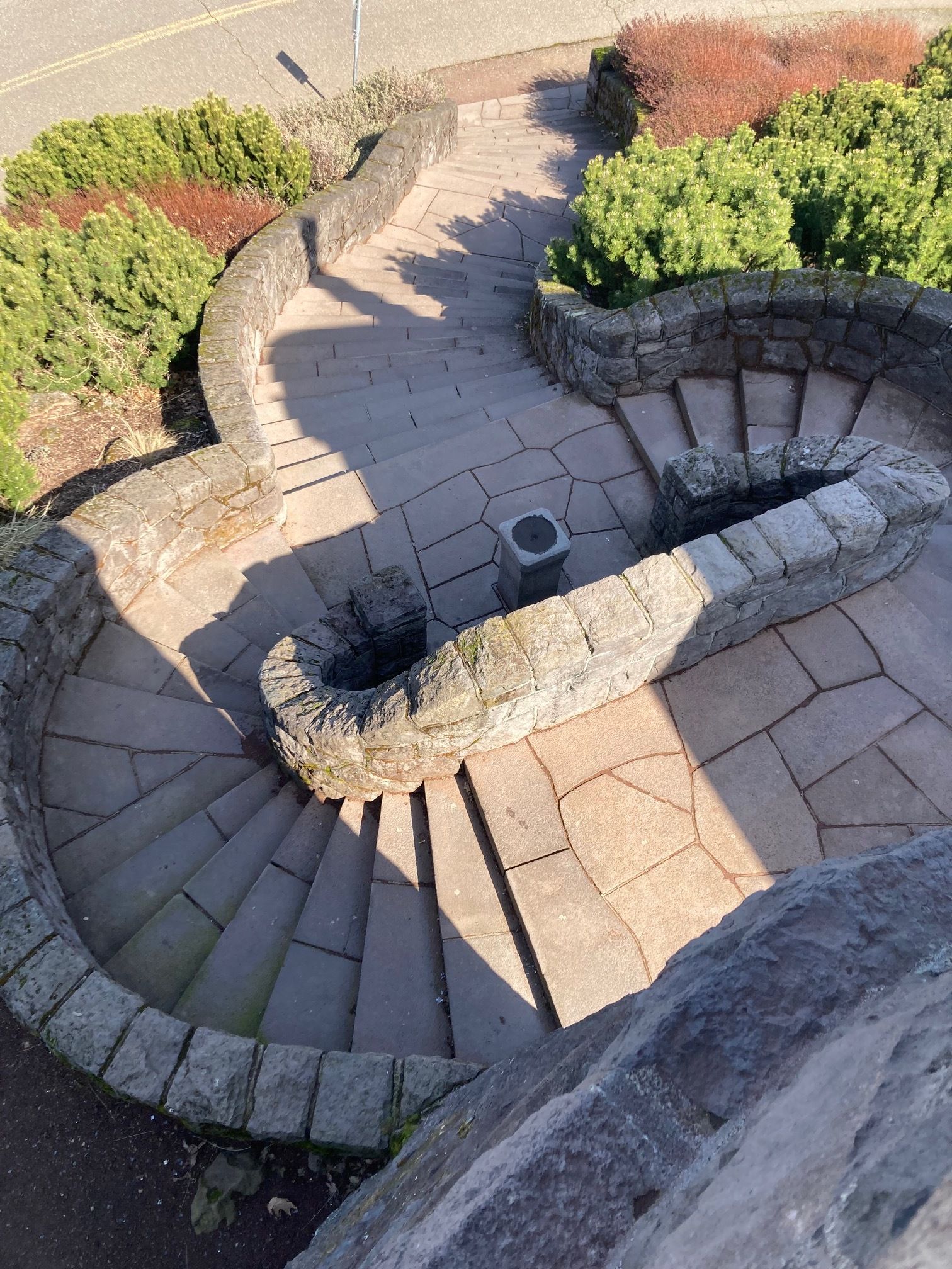 Two circular stone staircases meet and descend as one.