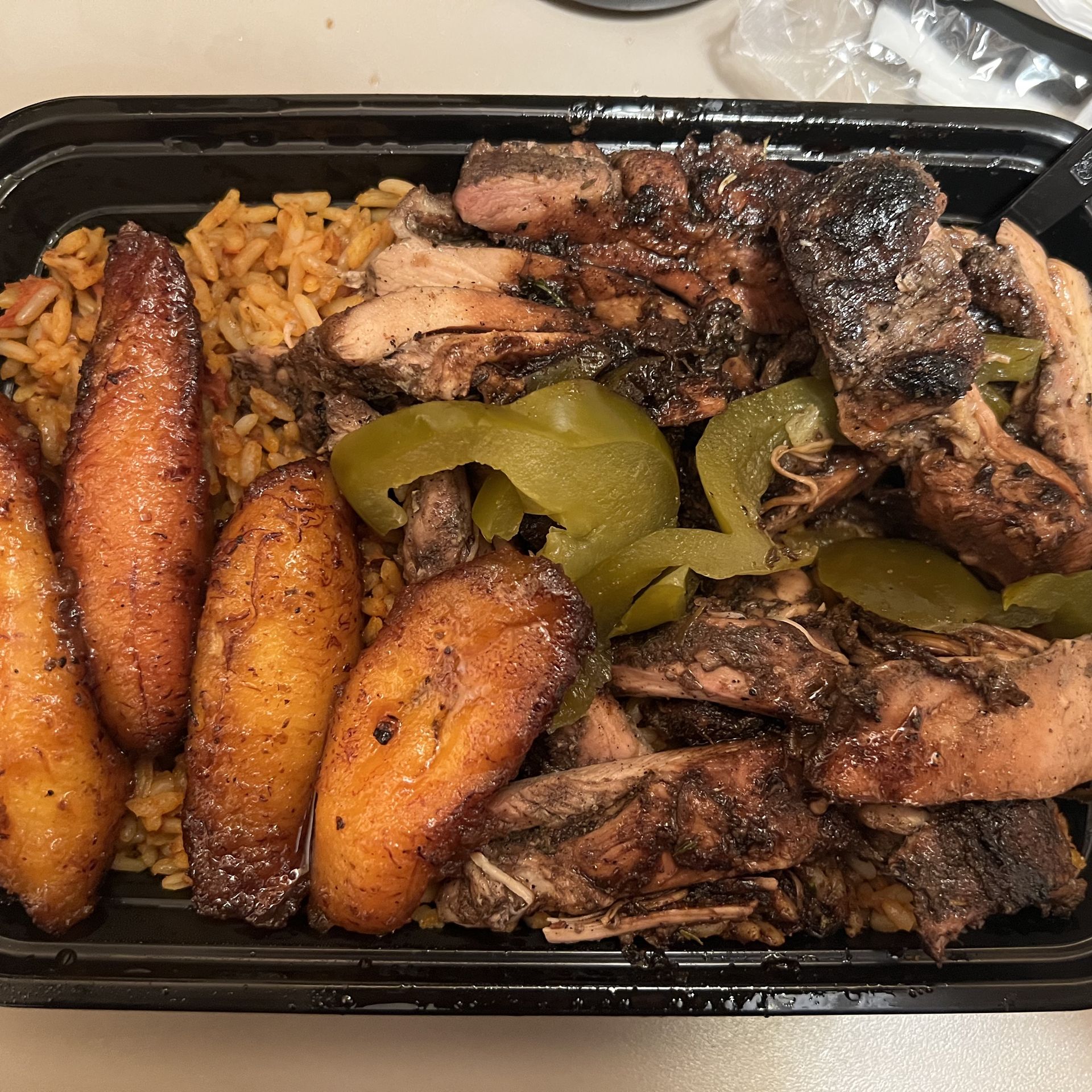Spicy jerk chicken and jollof rice with sweet plantains. Photo: Samuel Robinson/Axios