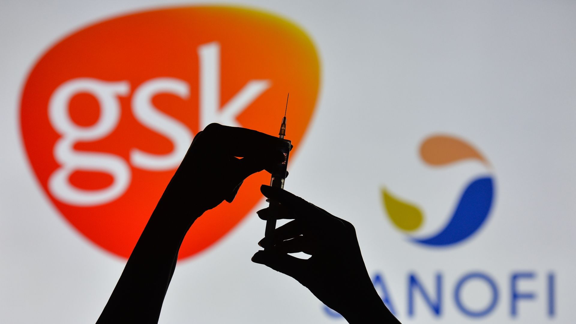 Picture of two hands holding a syringe with the Sanofi and GSK logos in the background