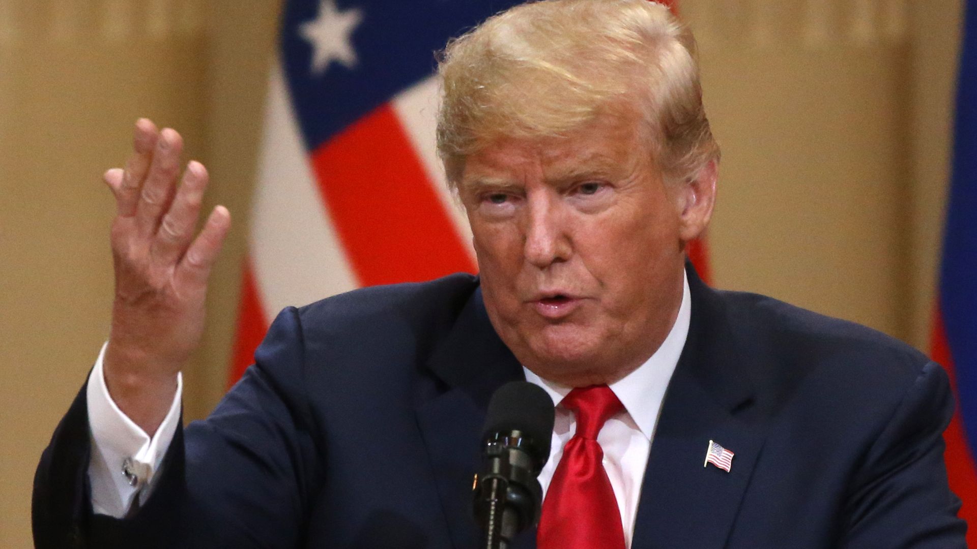 Donald Trump lifts his hand upward while speaking