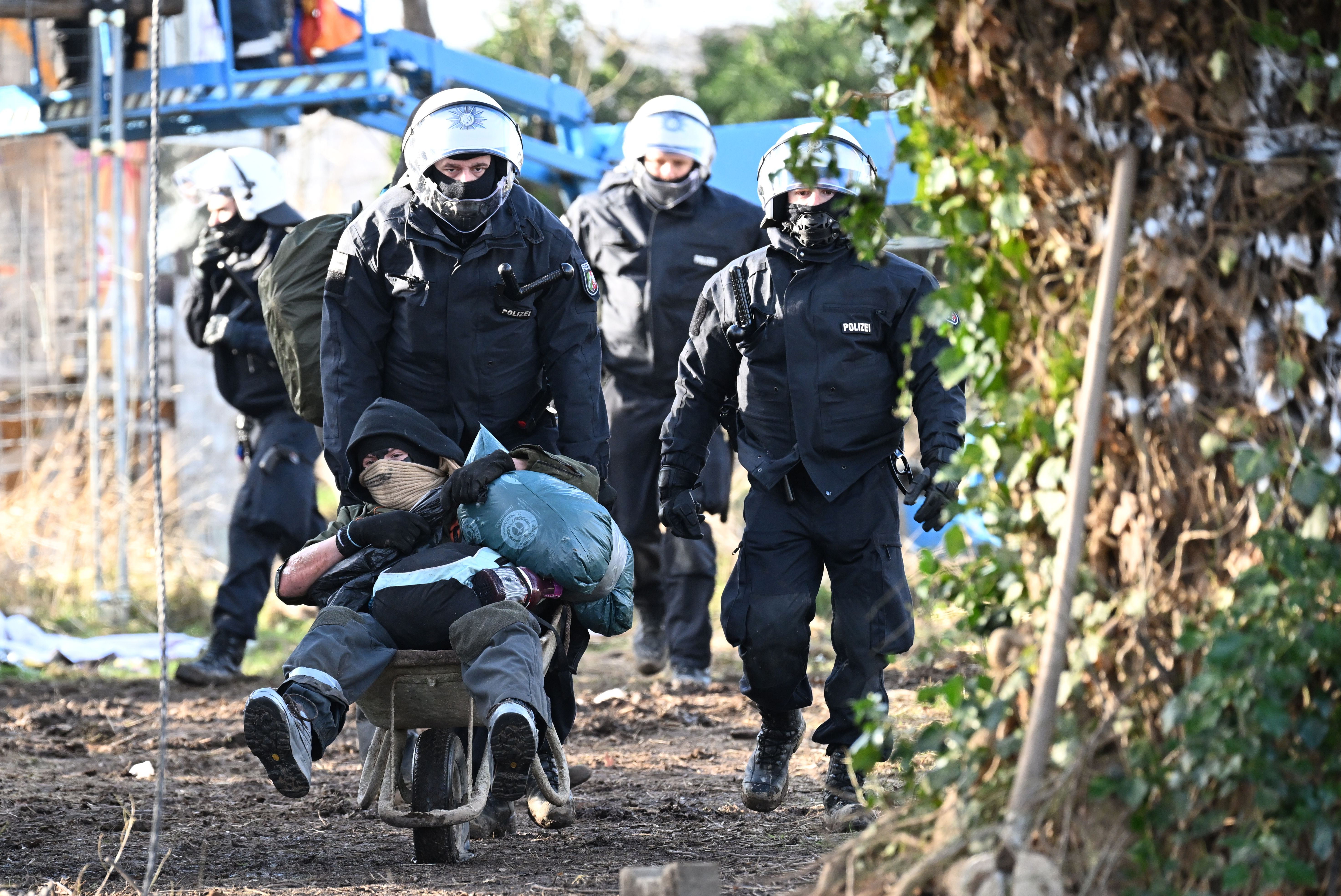 North Rhine-Westphalia, Erkelenz: Police officers push a climate activist with a wheelbarrow from the site in Lützerath. 