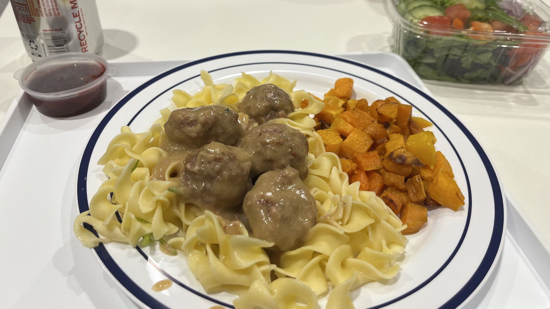 A plate of swedish meatballs, butternut squash and a side salad 