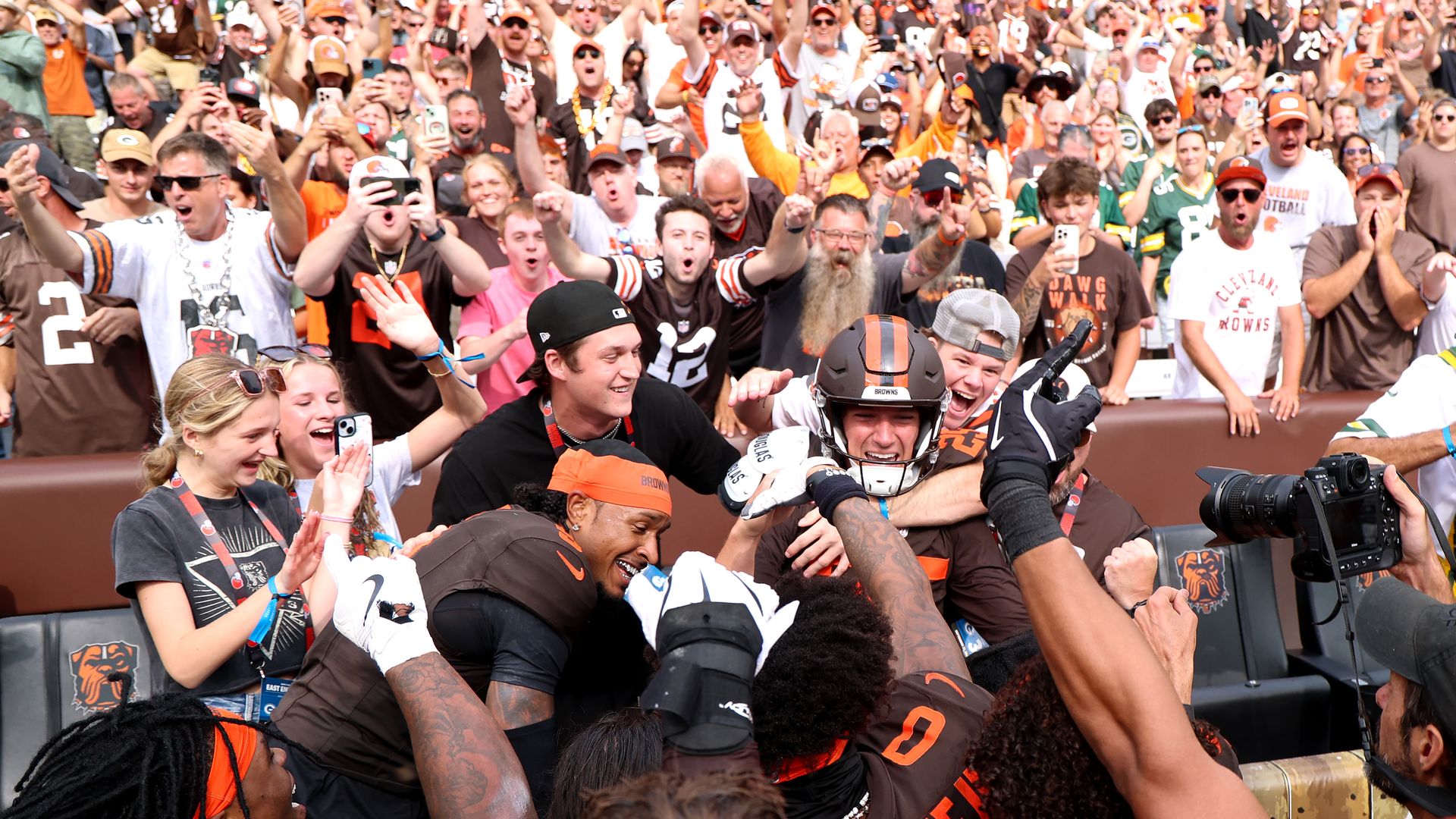 Browns teammates and fans celebrate in a mob after a win. 