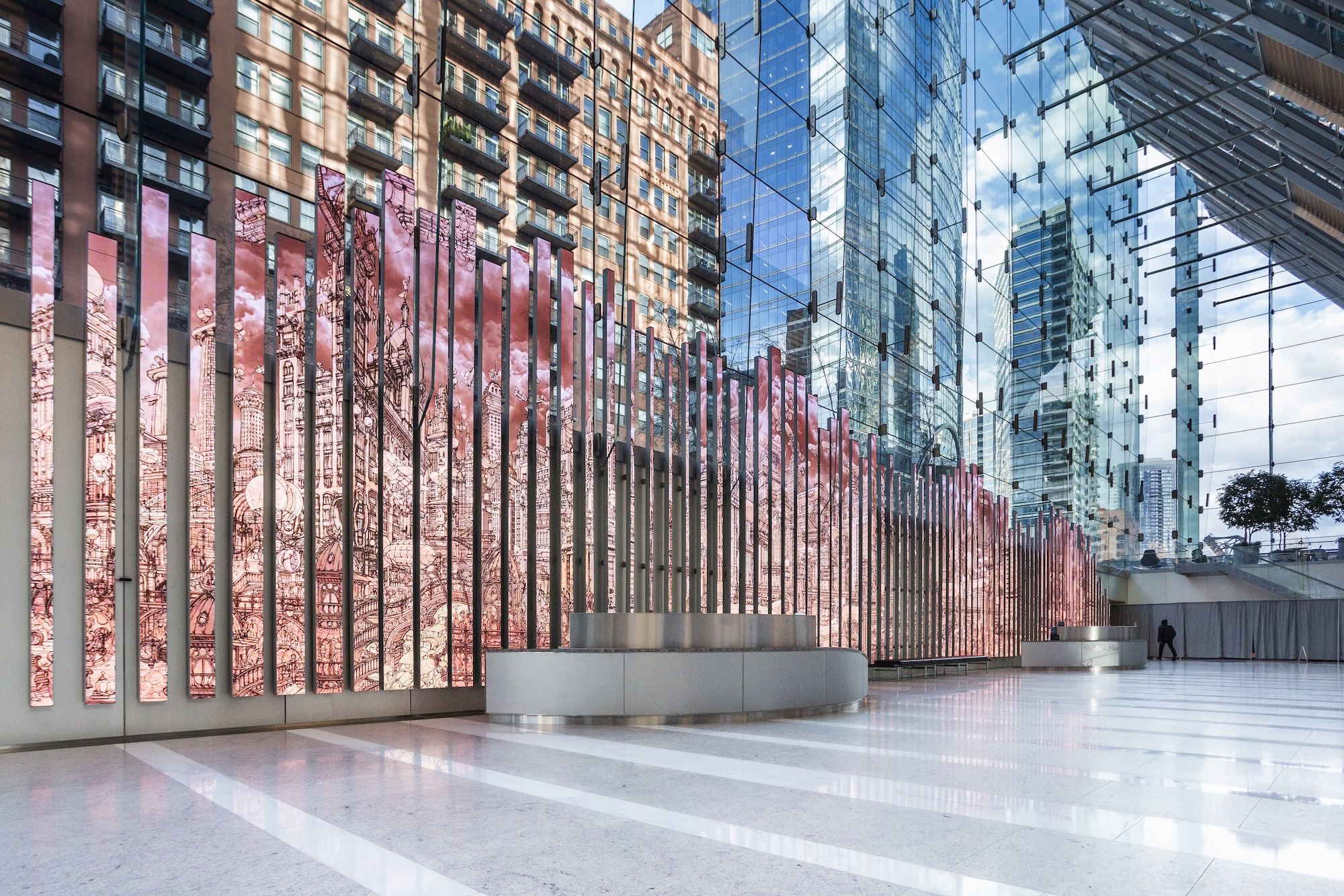 Vertical panels that have images digitally animated on them in the lobby of a modern office building surrounded by glass.
