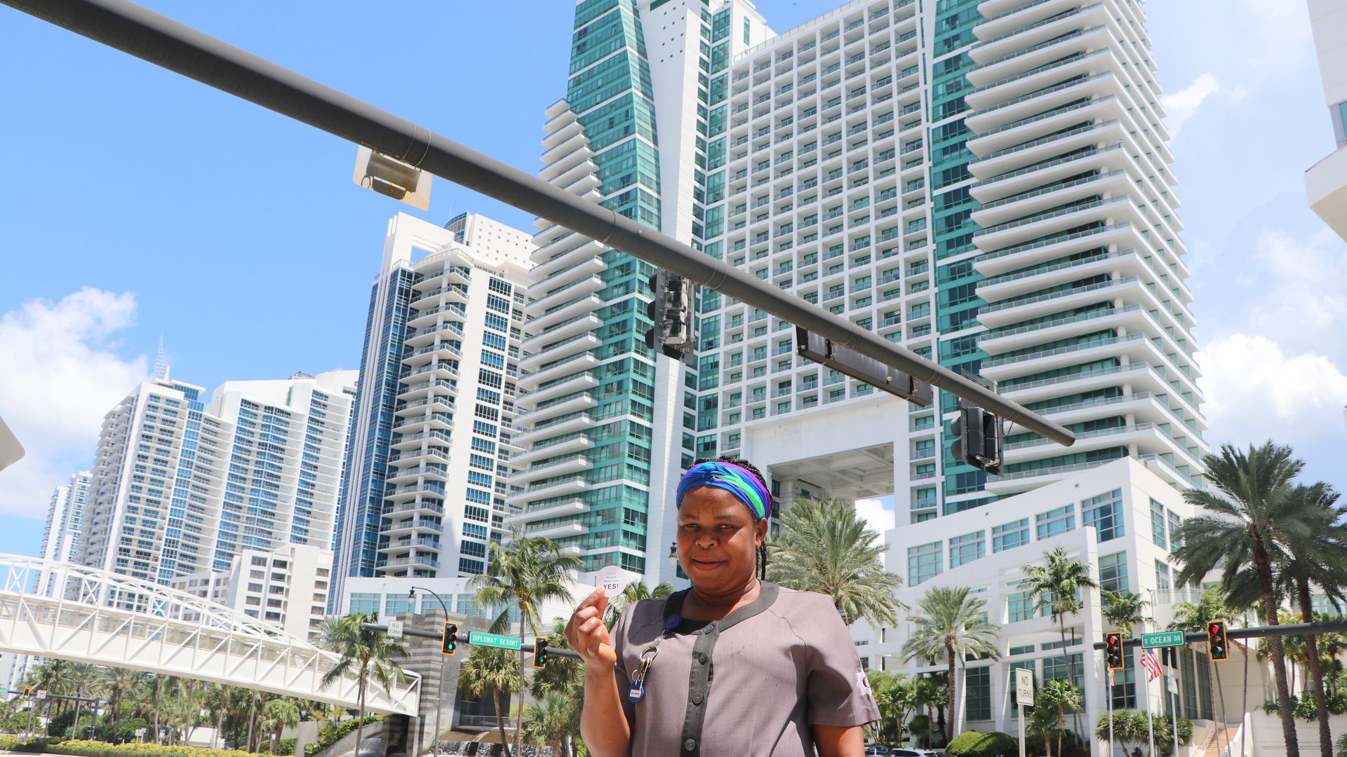 A worker in a gray uniform stands in front of the white and turquoise Diplomat Resort.