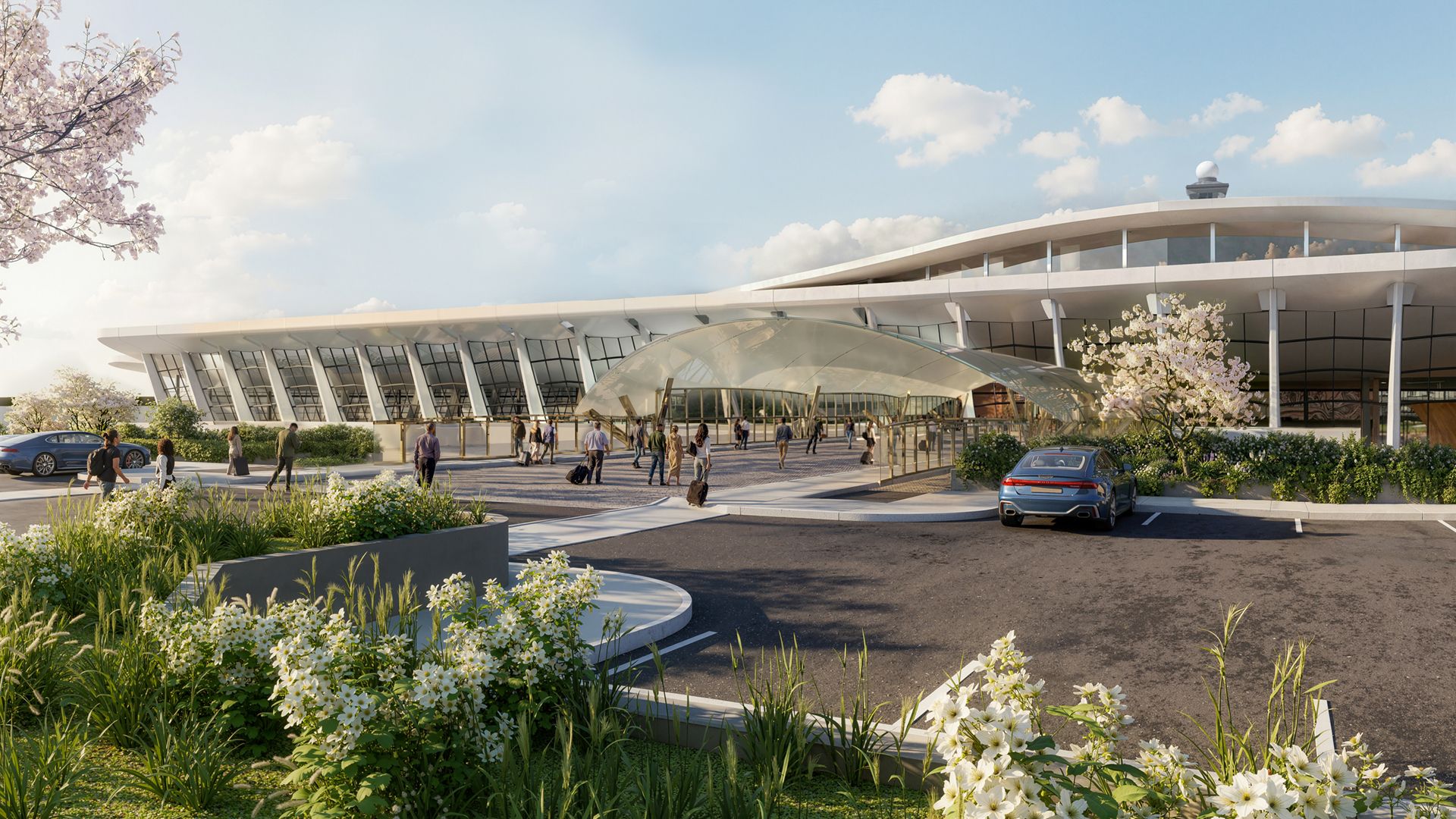 Modern airport-style building with a curved white roof, glass walls, and an entrance canopy. People with luggage walk by a blue car in the parking lot; blooming trees and white flowers in foreground.