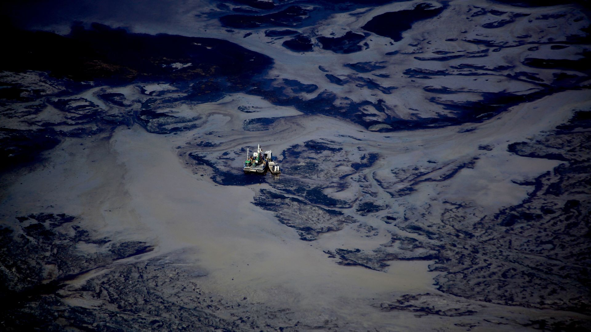 A utility barge sits in a tailing pond at the Syncrude open pit oil excavation mine in Fort McMurray