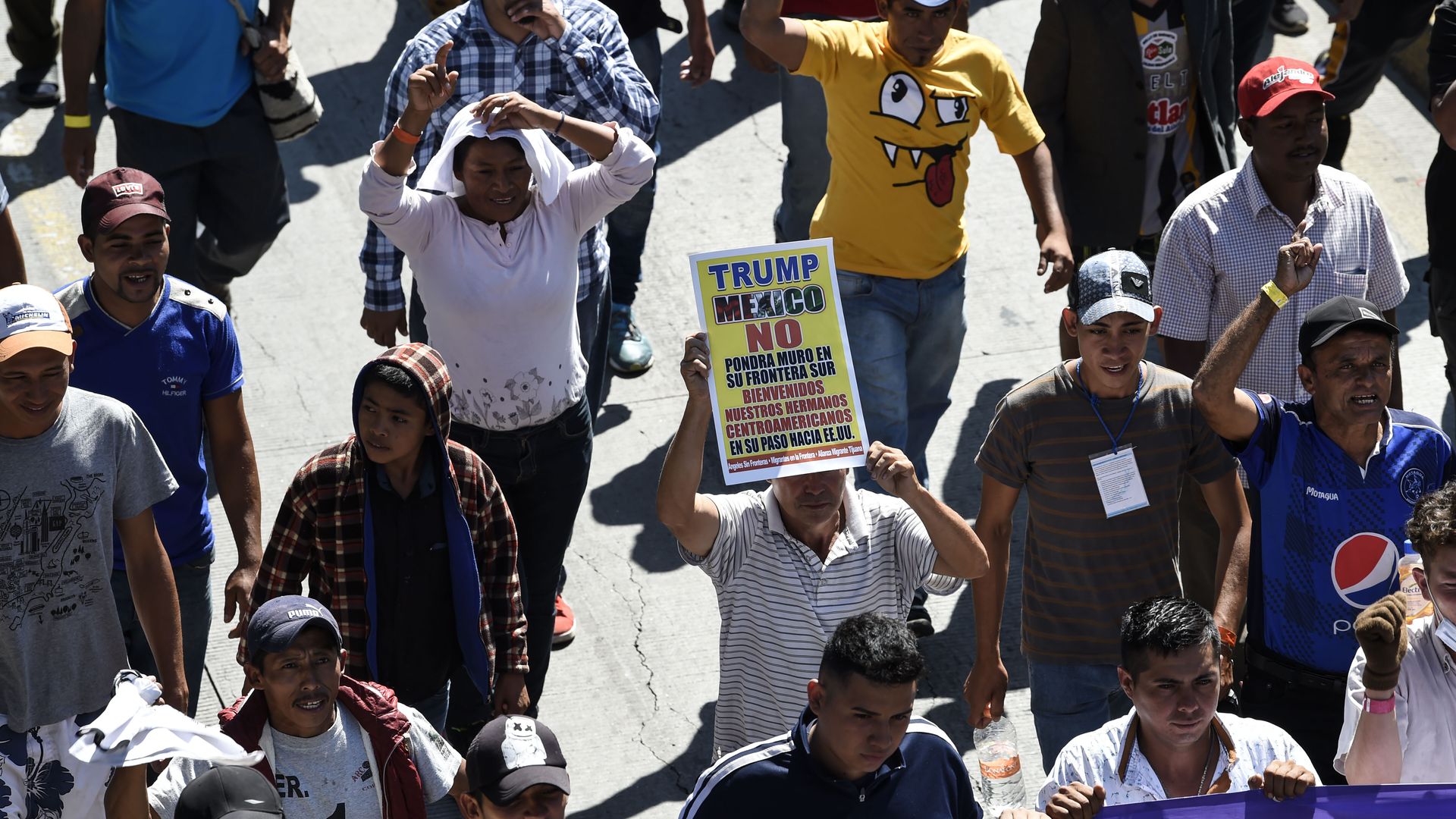 Members of the caravan of Central American migrants walking down a road. 