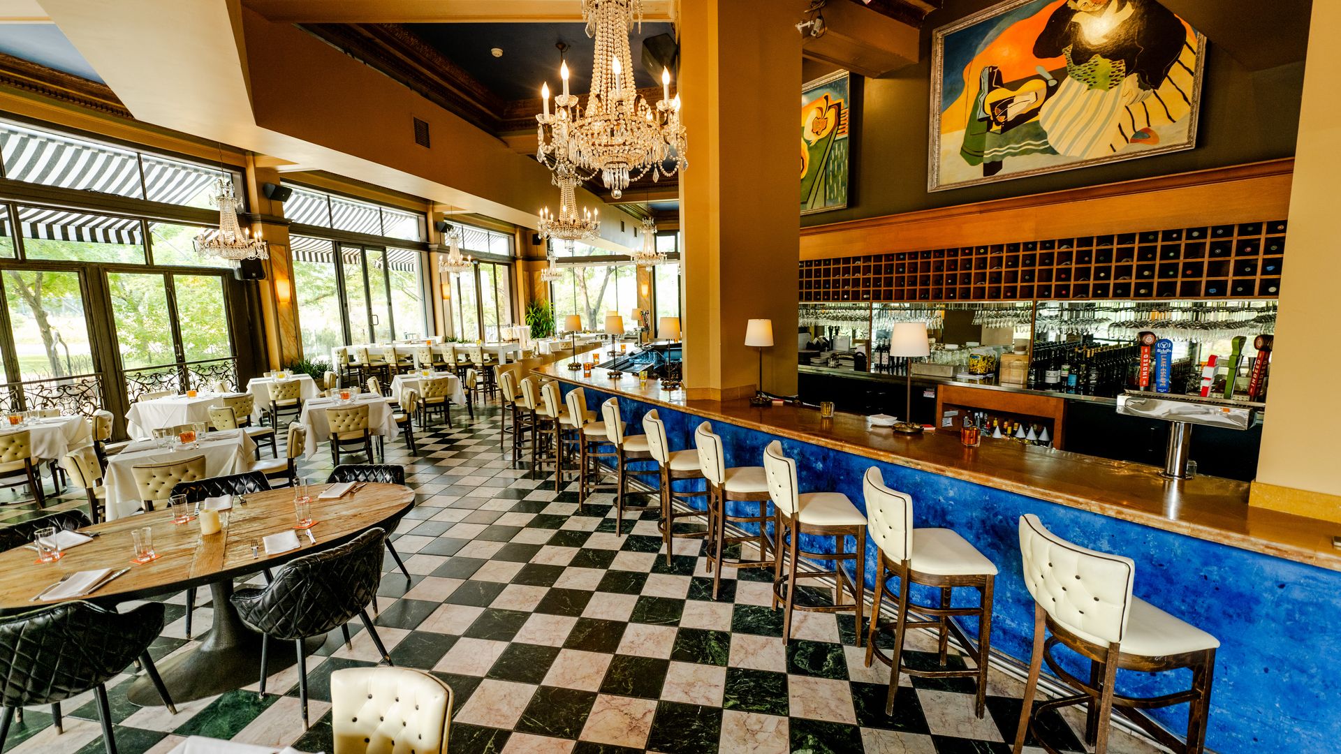 The interior of Cafe and Bar Lurcat, which has checkered floors, white barstools and wooden tables.