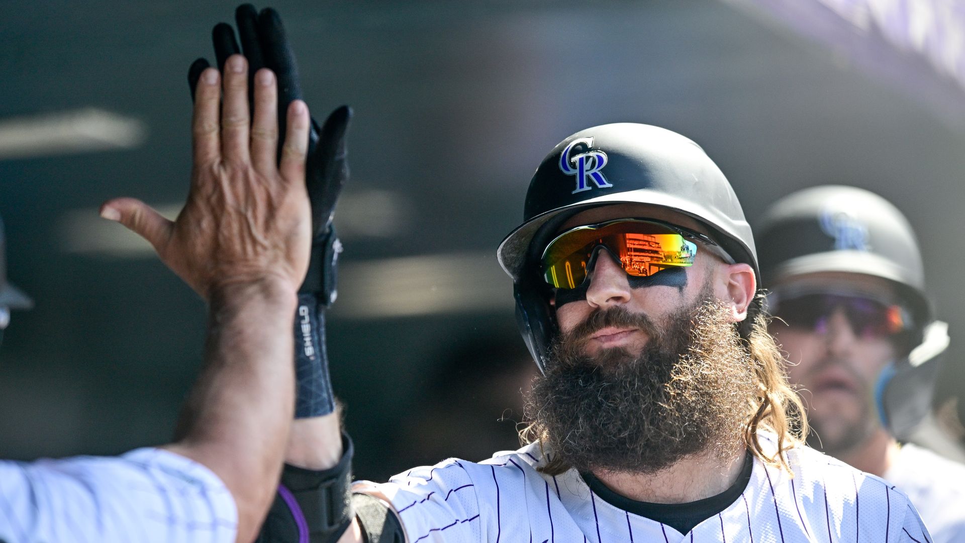 A man with sunglasses and a hat high-fives another man. 