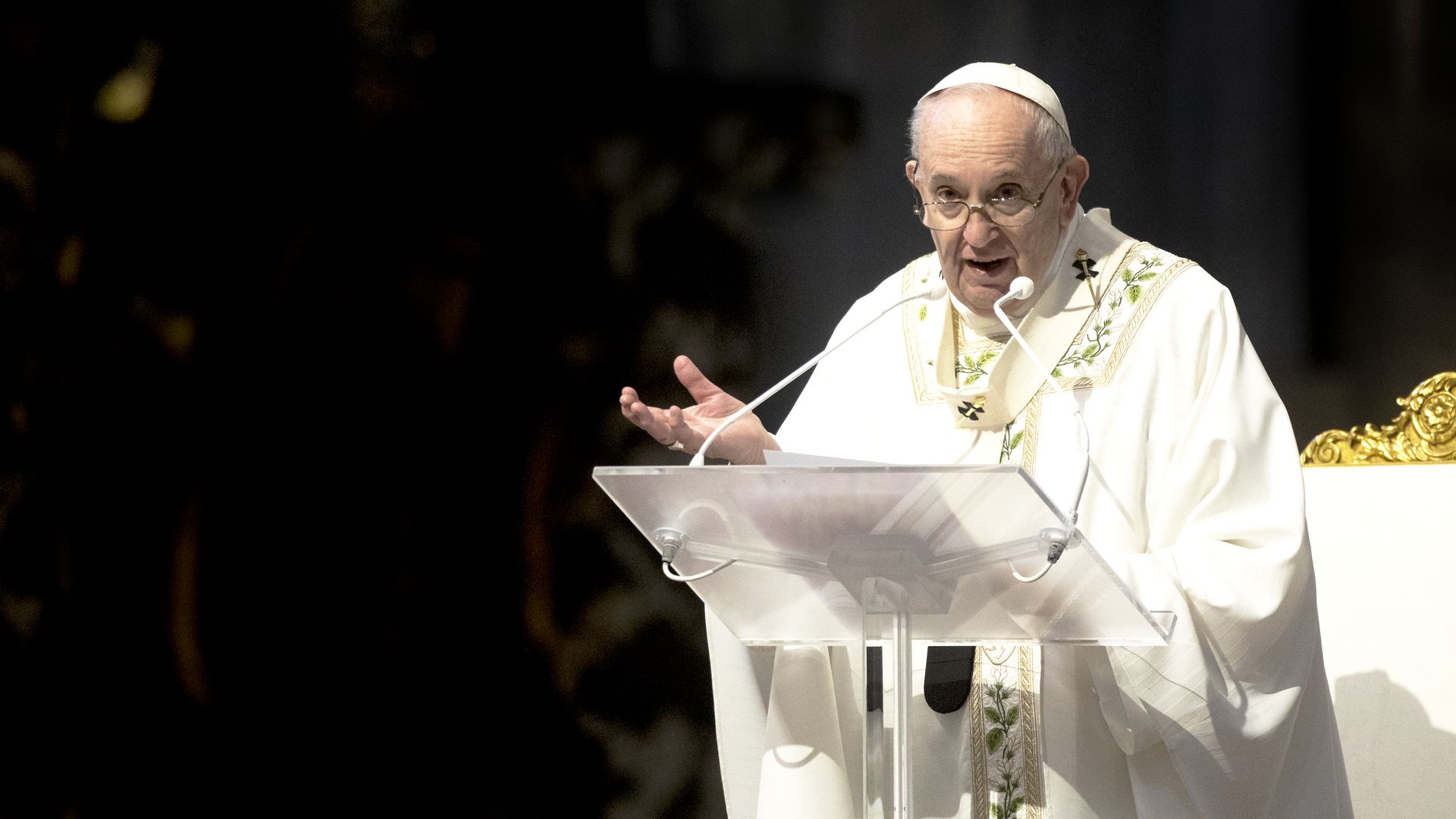 Pope Francis stands at a podium, speaking.