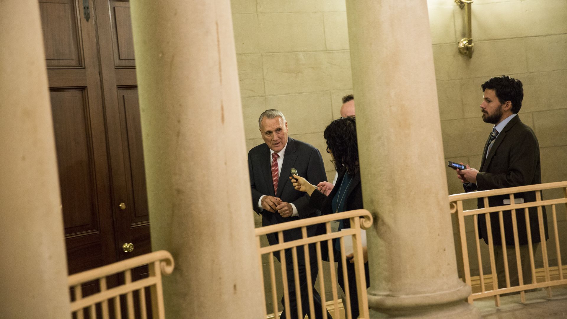Jon Kyl walks behind columns