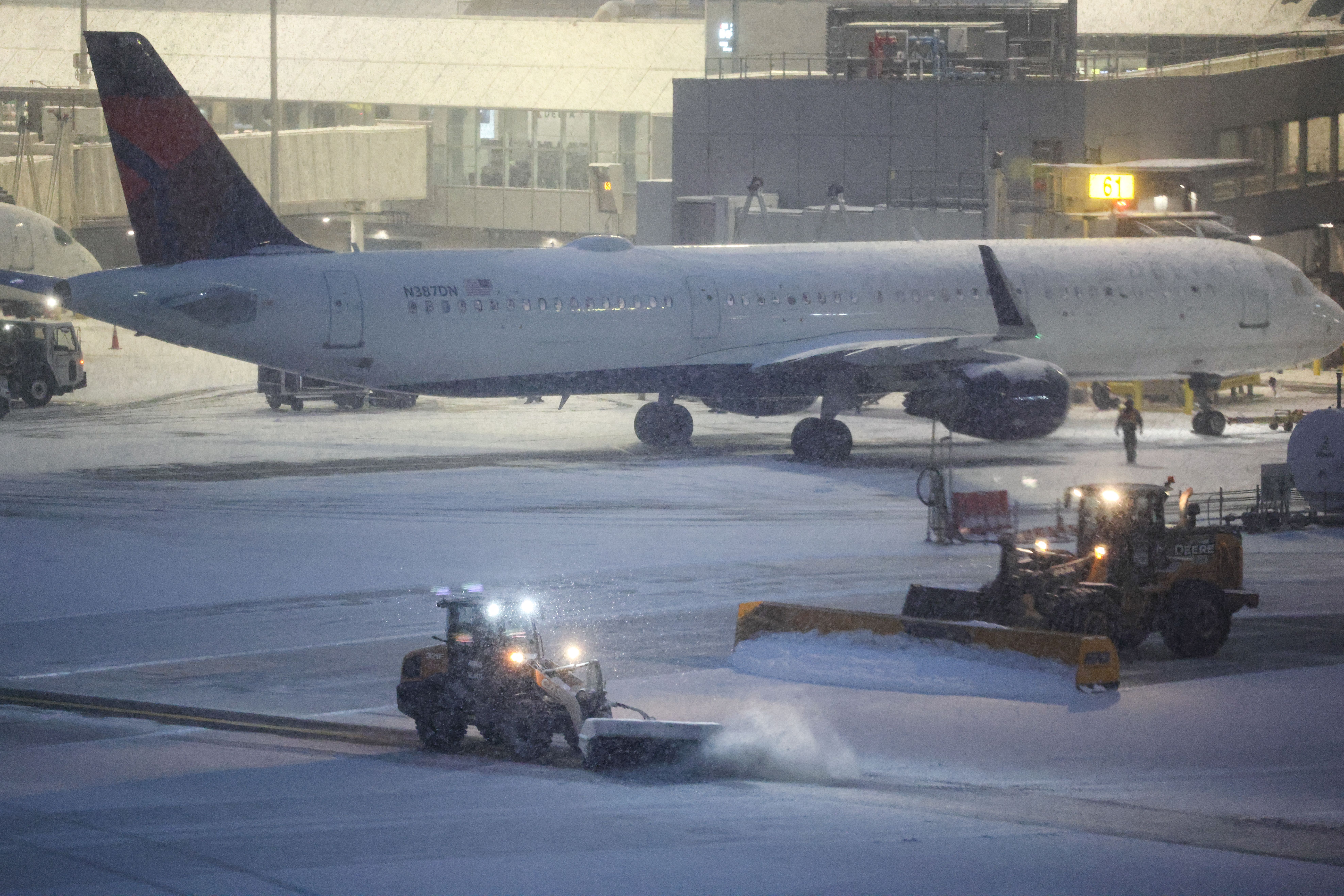 Snow removal machines are seen working on the tarmac of LaGuardia airport in New York on January 25, 2026.