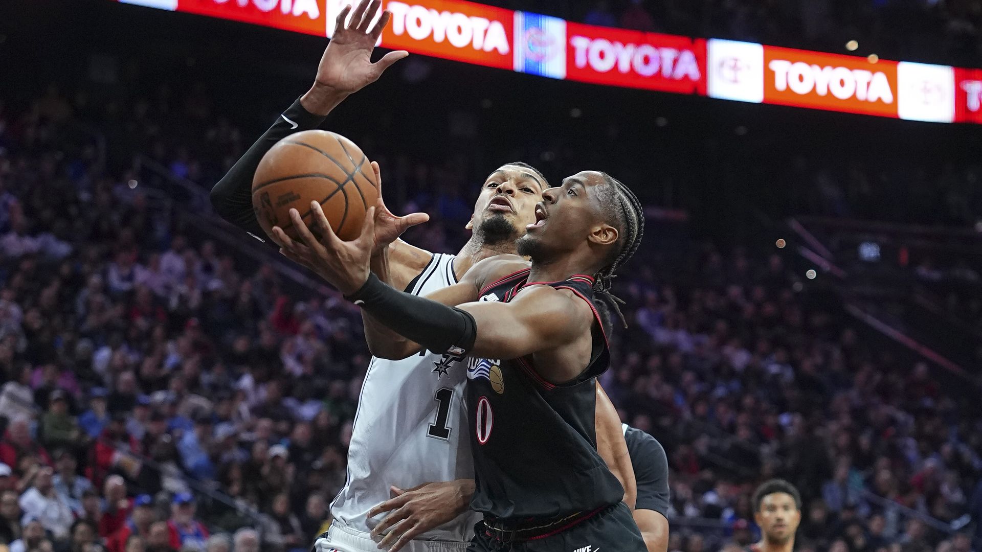 The Sixers' Tyrese Maxey puts up a driving scoop shot over' Victor Wembanyama in last night's loss to the Spurs.