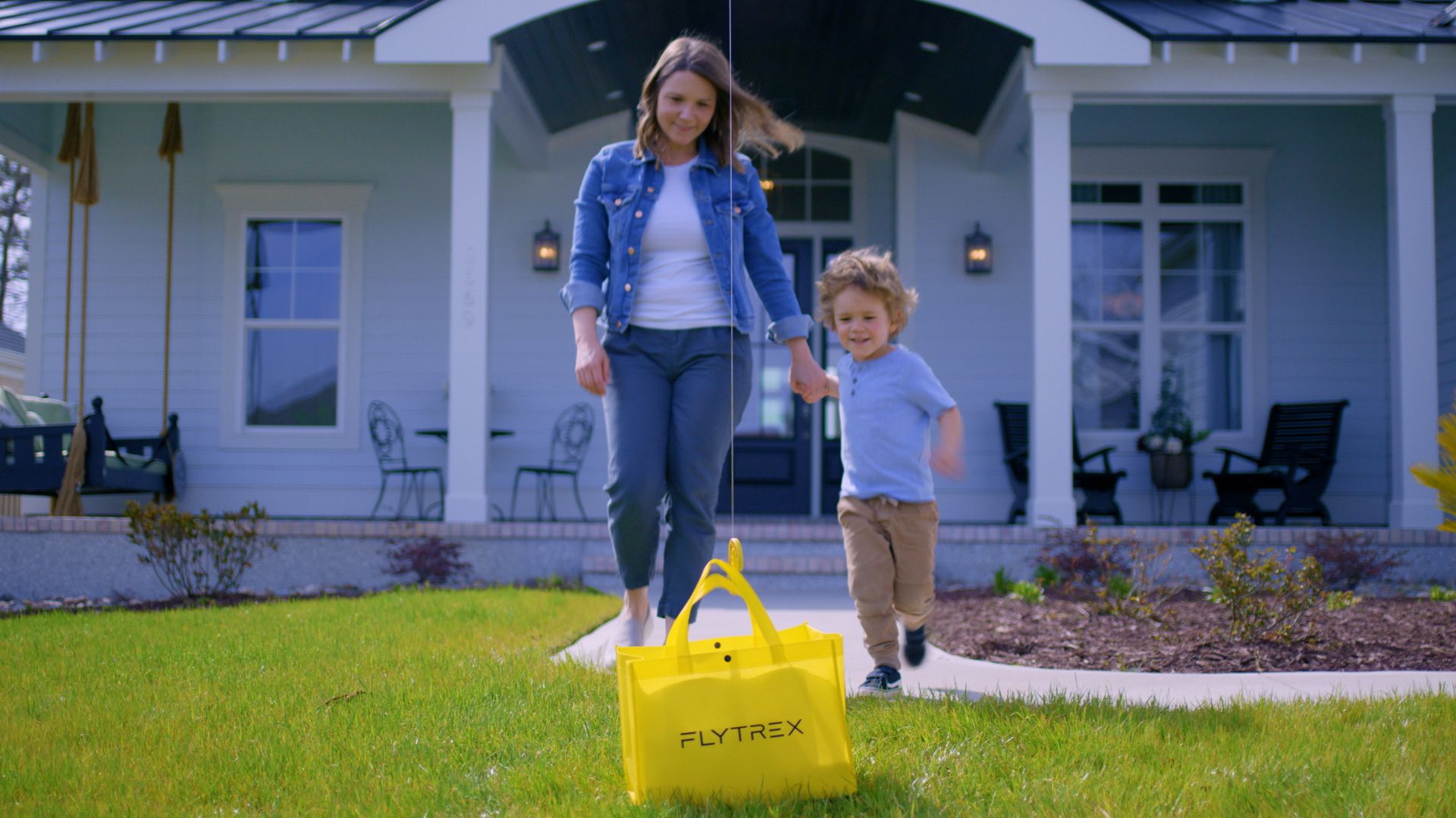 A woman and boy approach a bag of food lowered from a cable