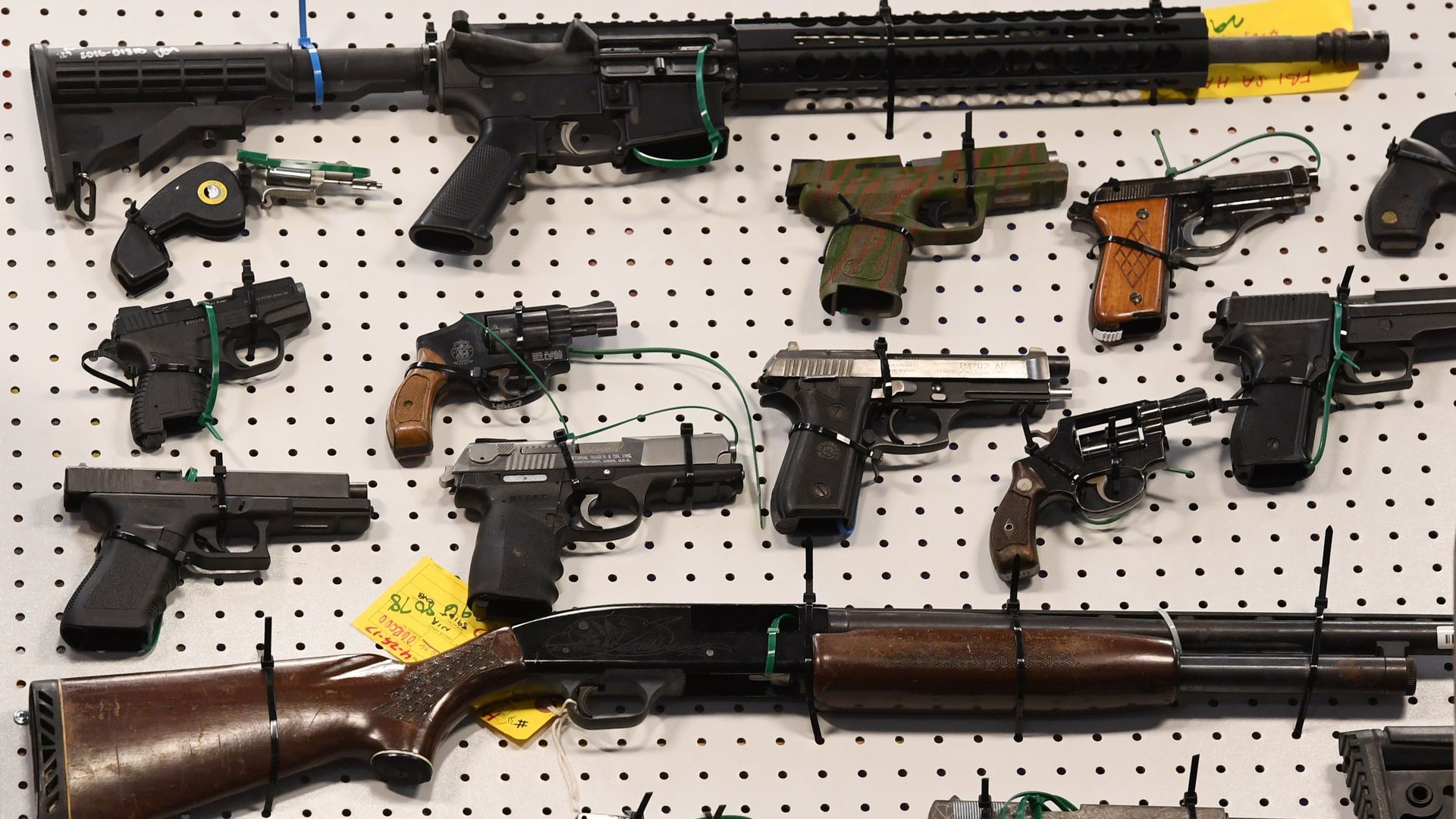 Handguns and rifles strapped to a wall.