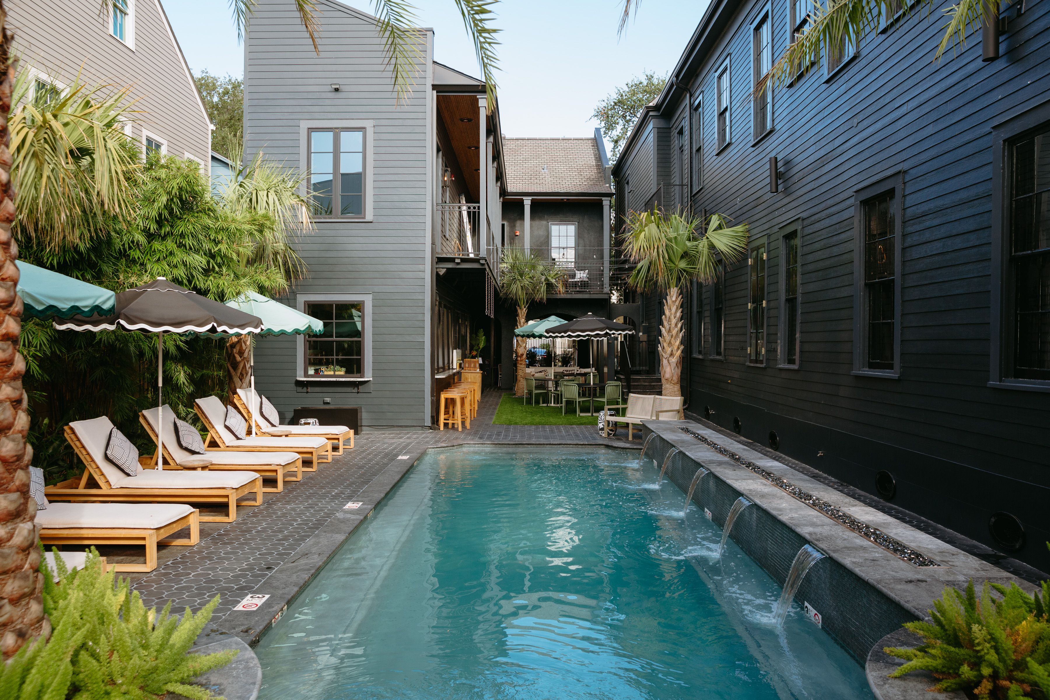 The back of a hotel building with a pool and loungers.