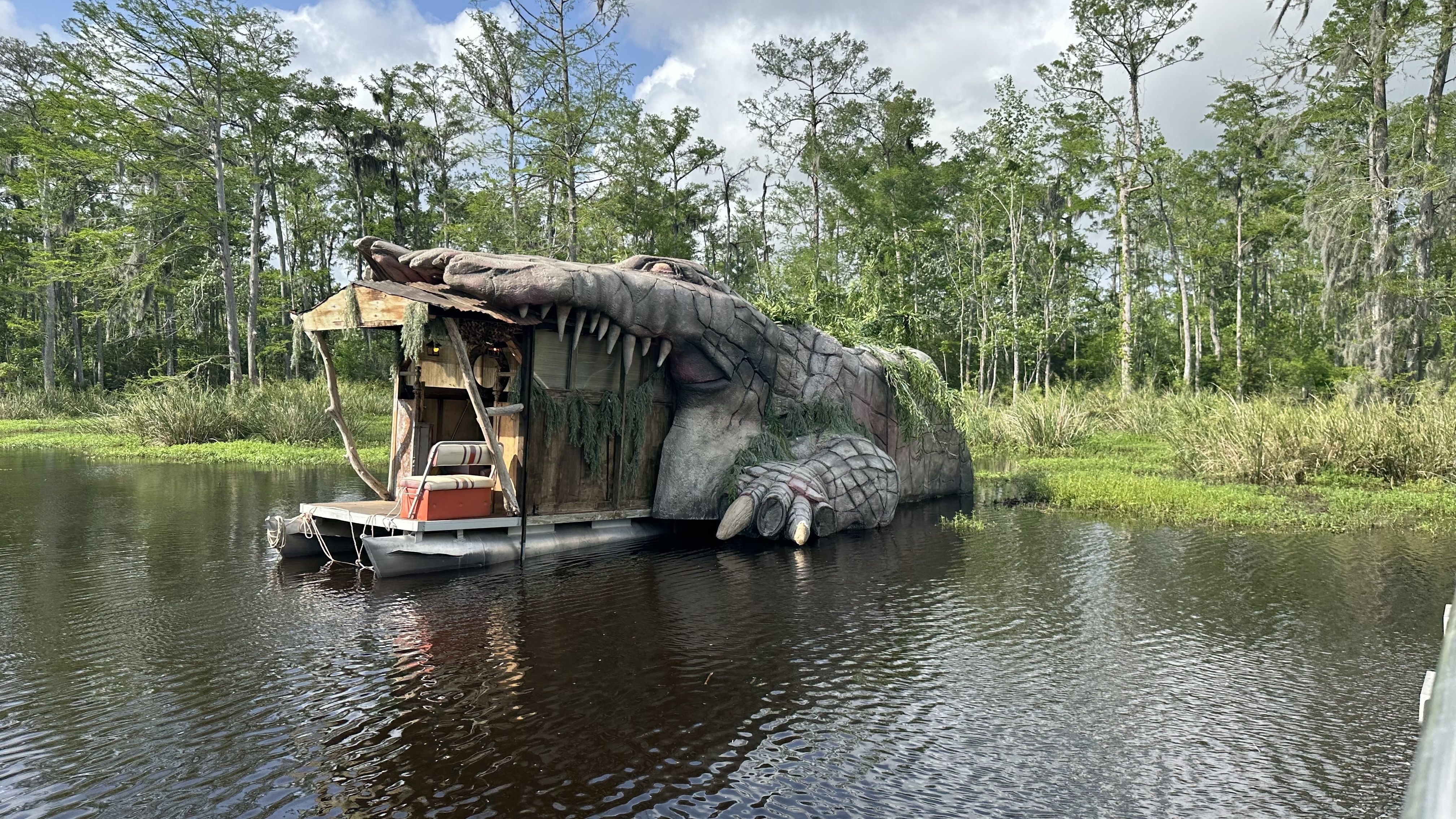 An alligator-shaped houseboat sits in an open bayou.