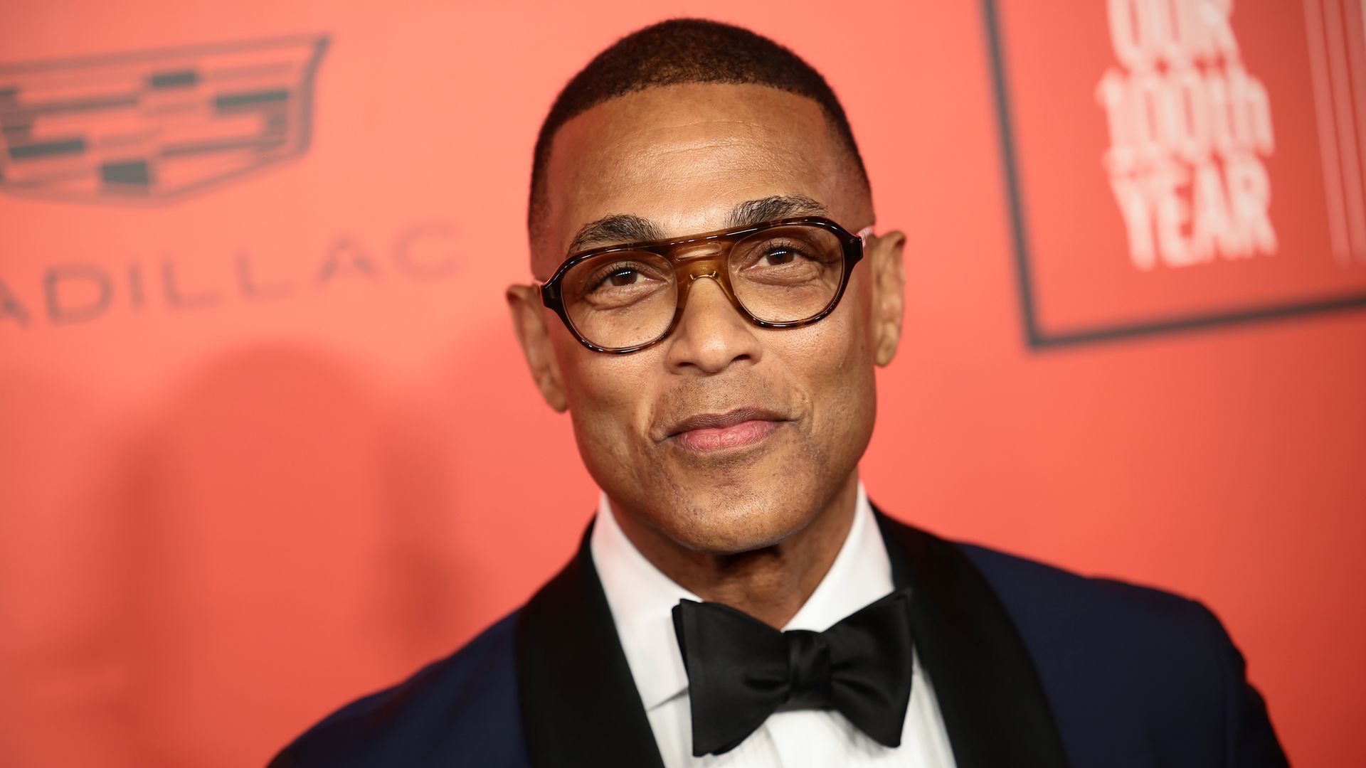 A man soft smiling in glasses and a tux.