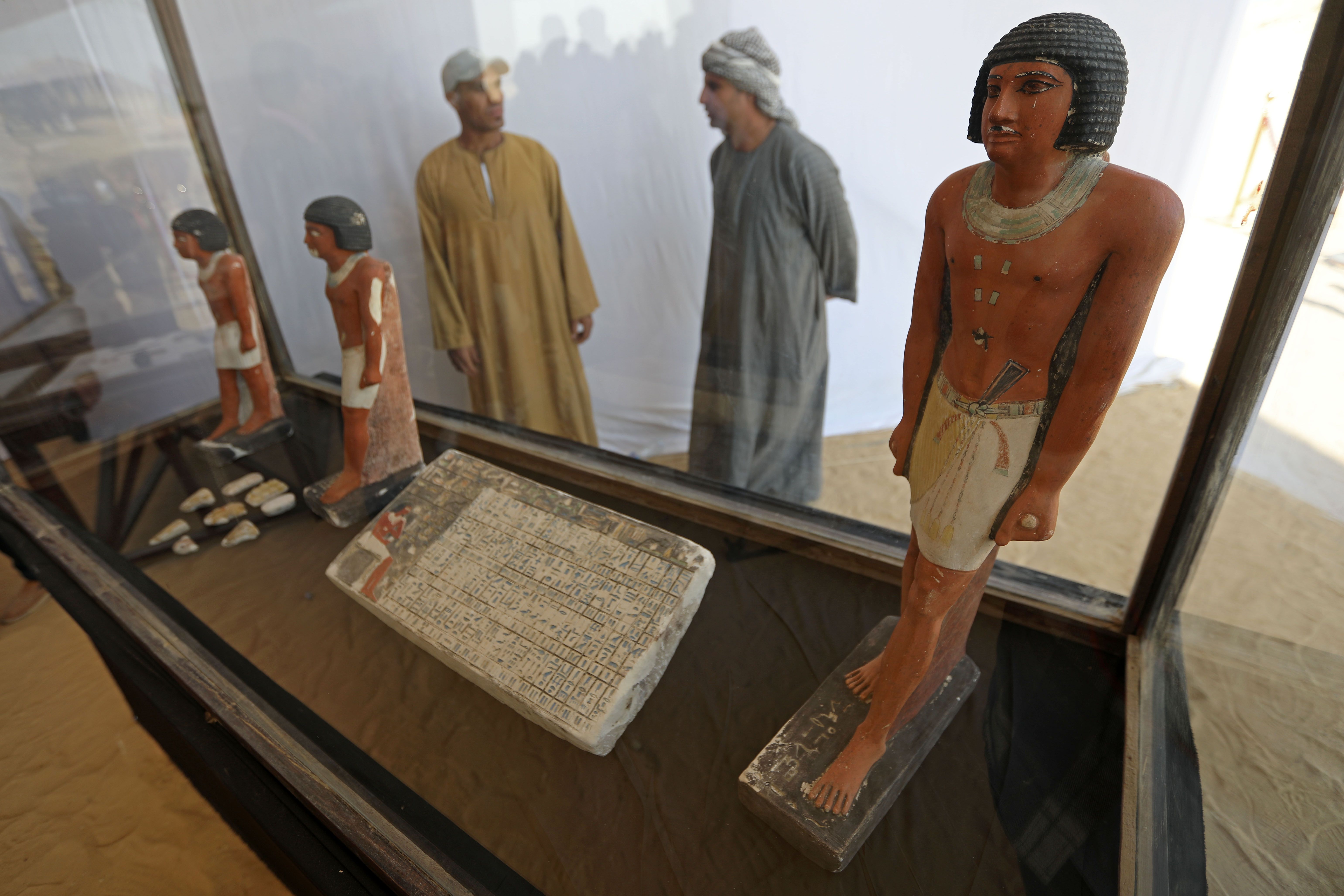 Egyptian antiquities workers observe recently discovered artifacts 