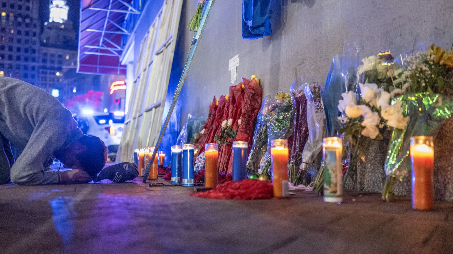 A man prays at a memorial with candles and flowers on Bourbon Street after the deadly car-ramming attack.