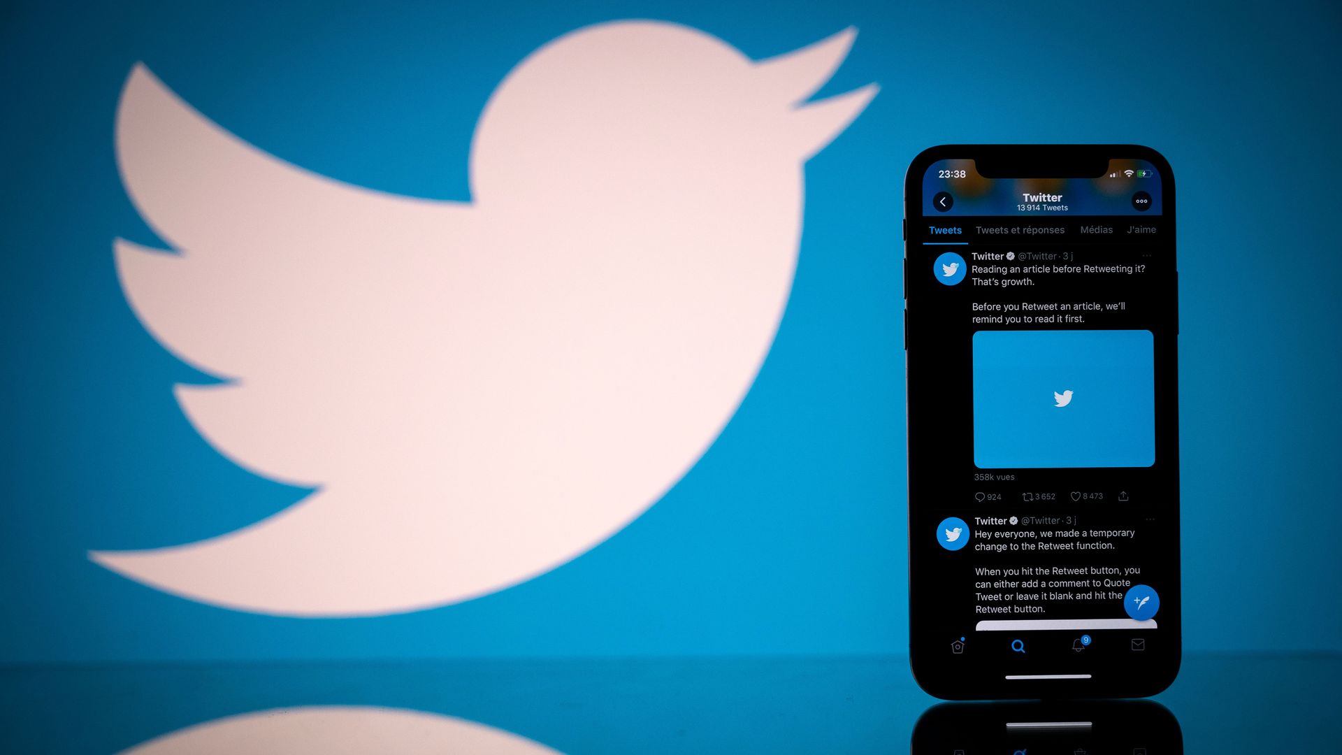 The Twitter logo and a phone in the foreground.