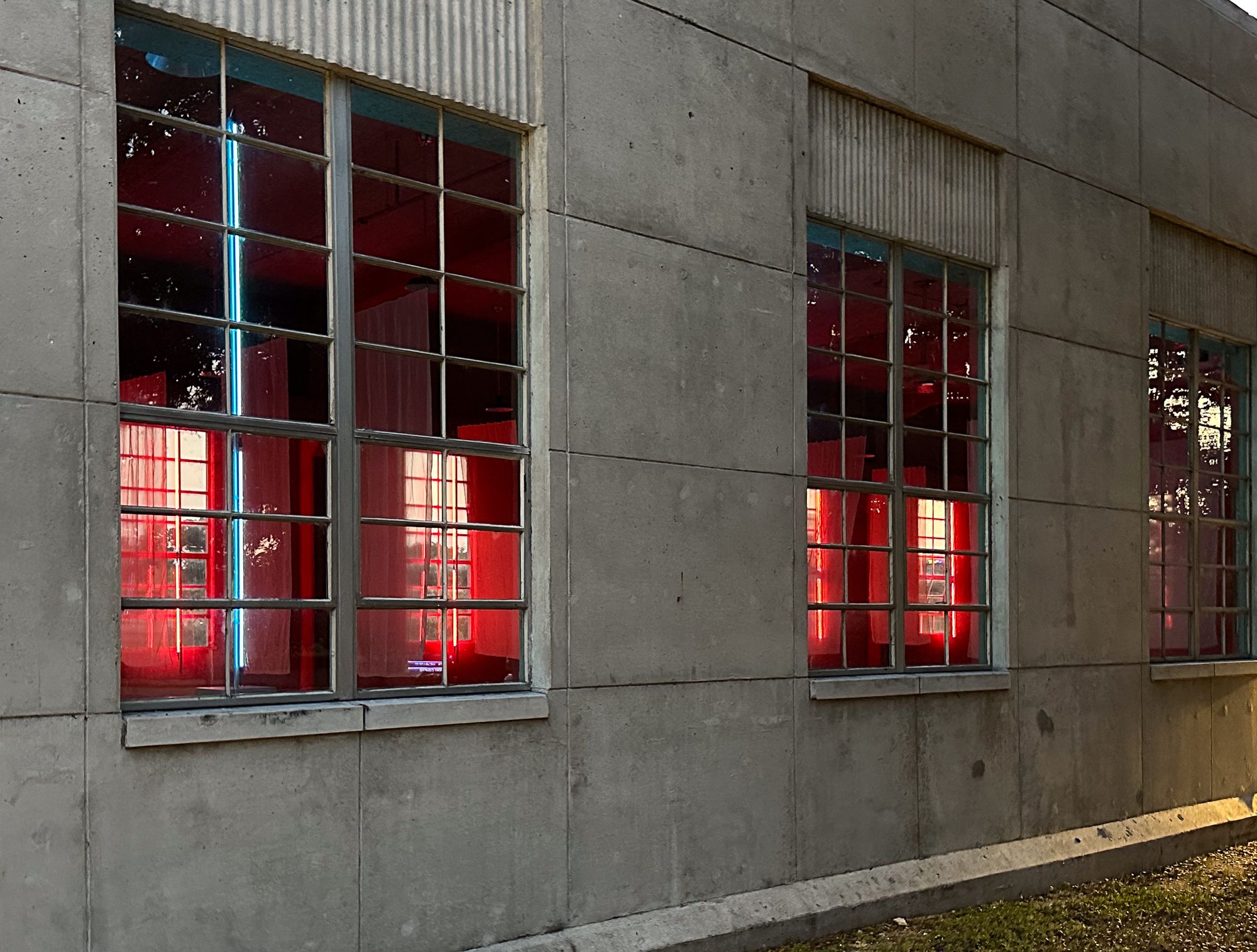 A photo of three windows with red light behind them.