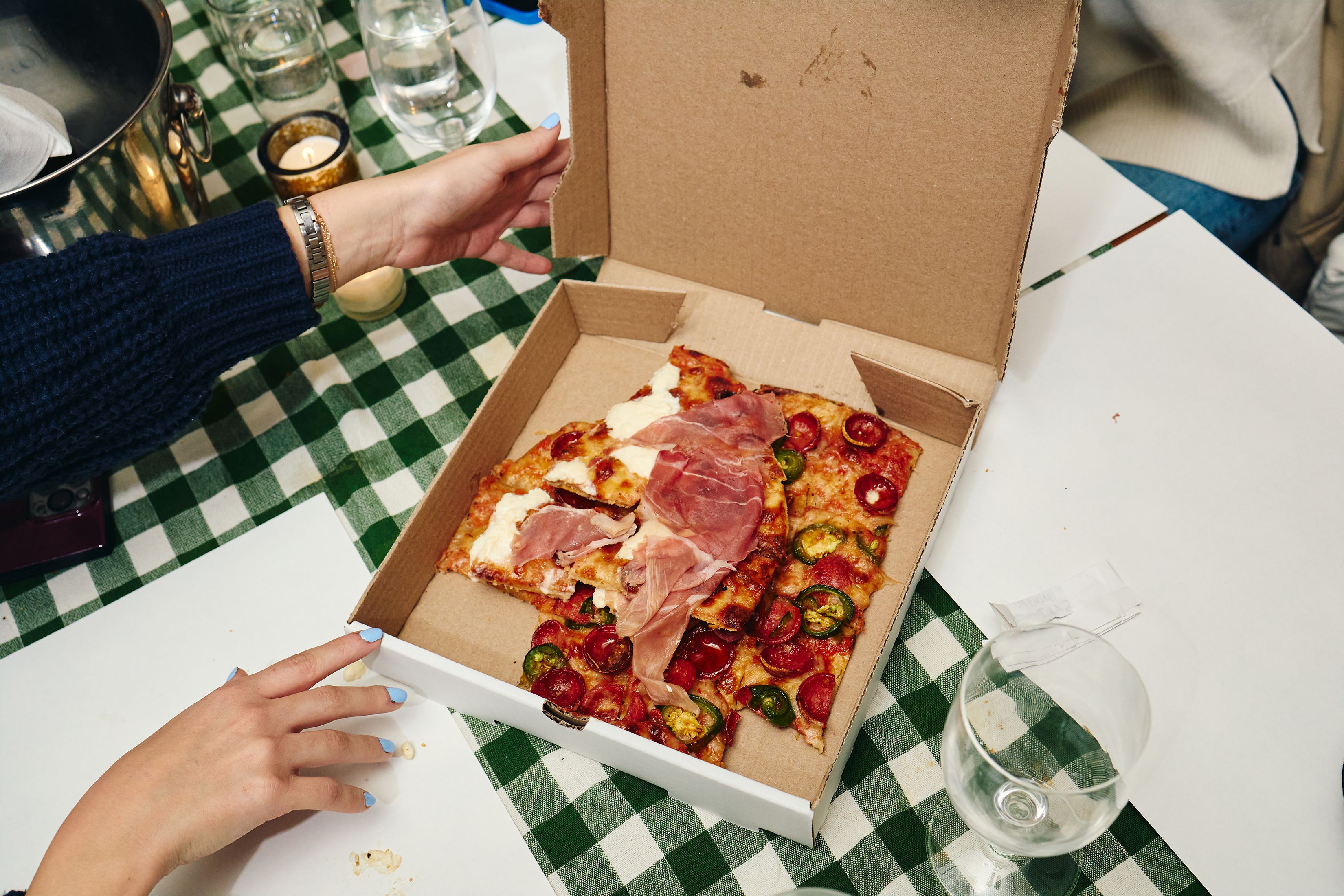 A diner opens her pizza box full of leftover pizza at Emmett's in New York on March 10, 2025. Restaurateurs in big cities have noticed a somewhat surprising shift in diner behavior.