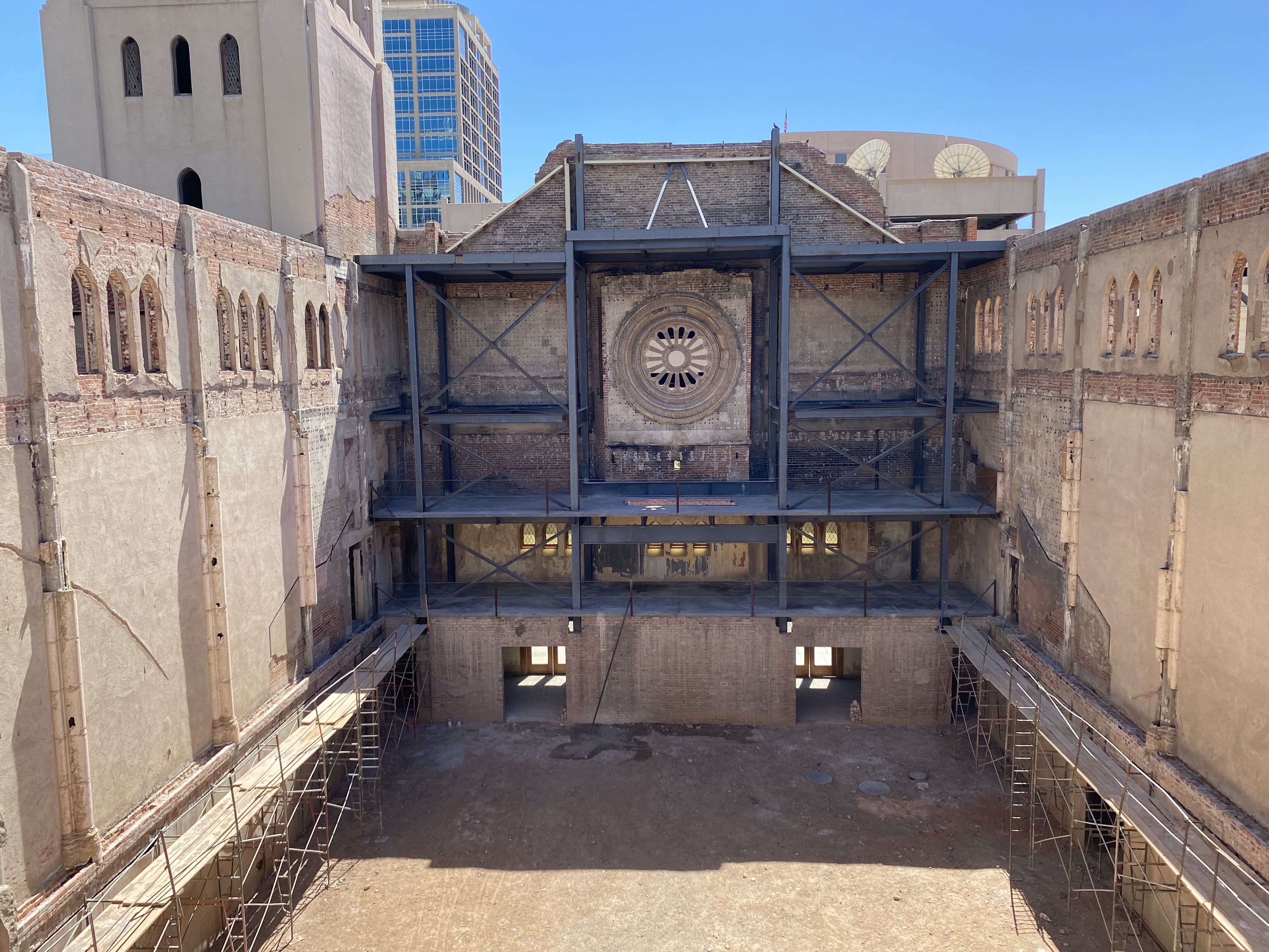 A dirt lot surrounded by five-story walls in the middle of a ruined church building. 